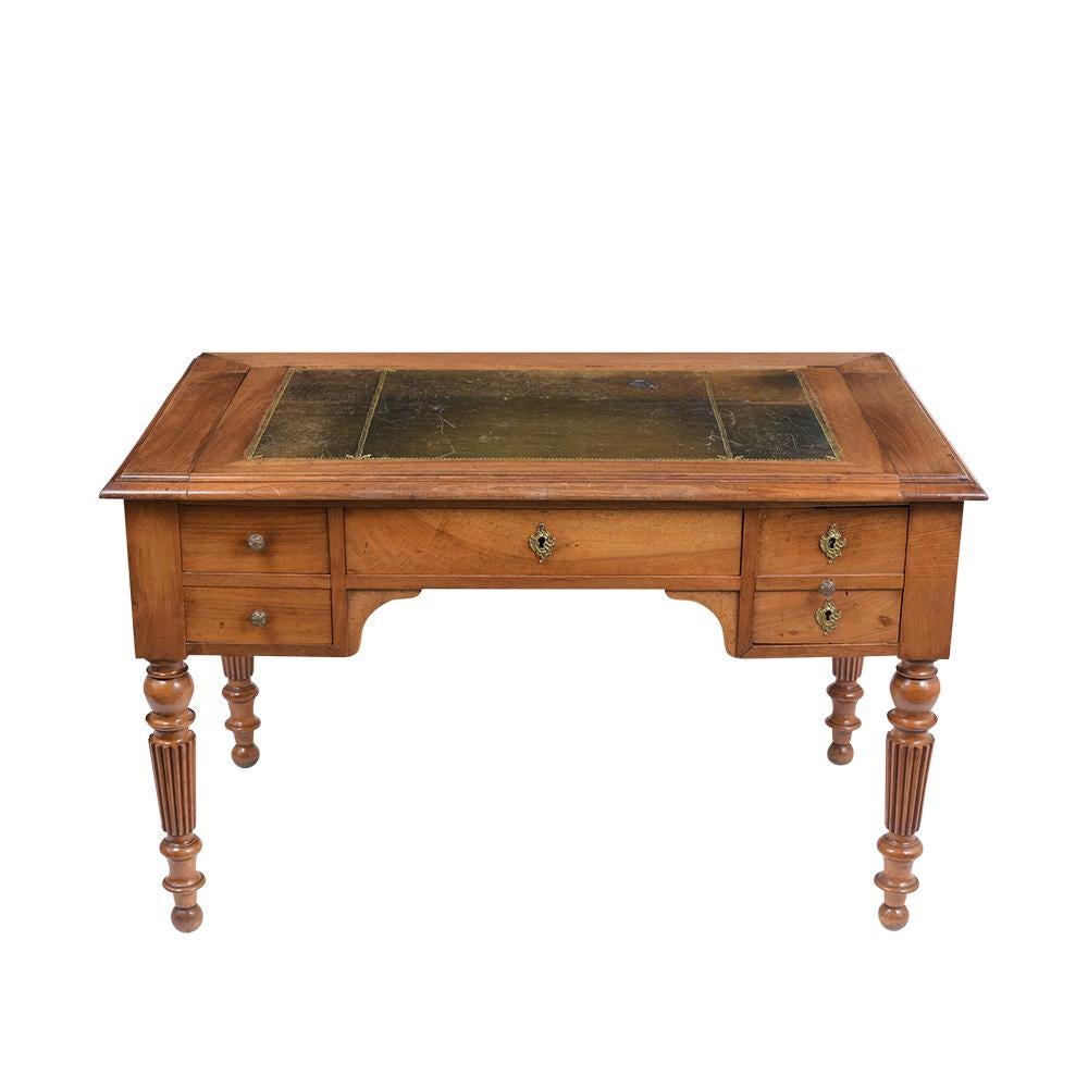 This is beautiful circa 1840s English desk made out of solid walnut wood with its original light walnut color and freshly waxed patina finish. The desktop has its original elegant dark green embossed leather with gilt trim and features four drawers,