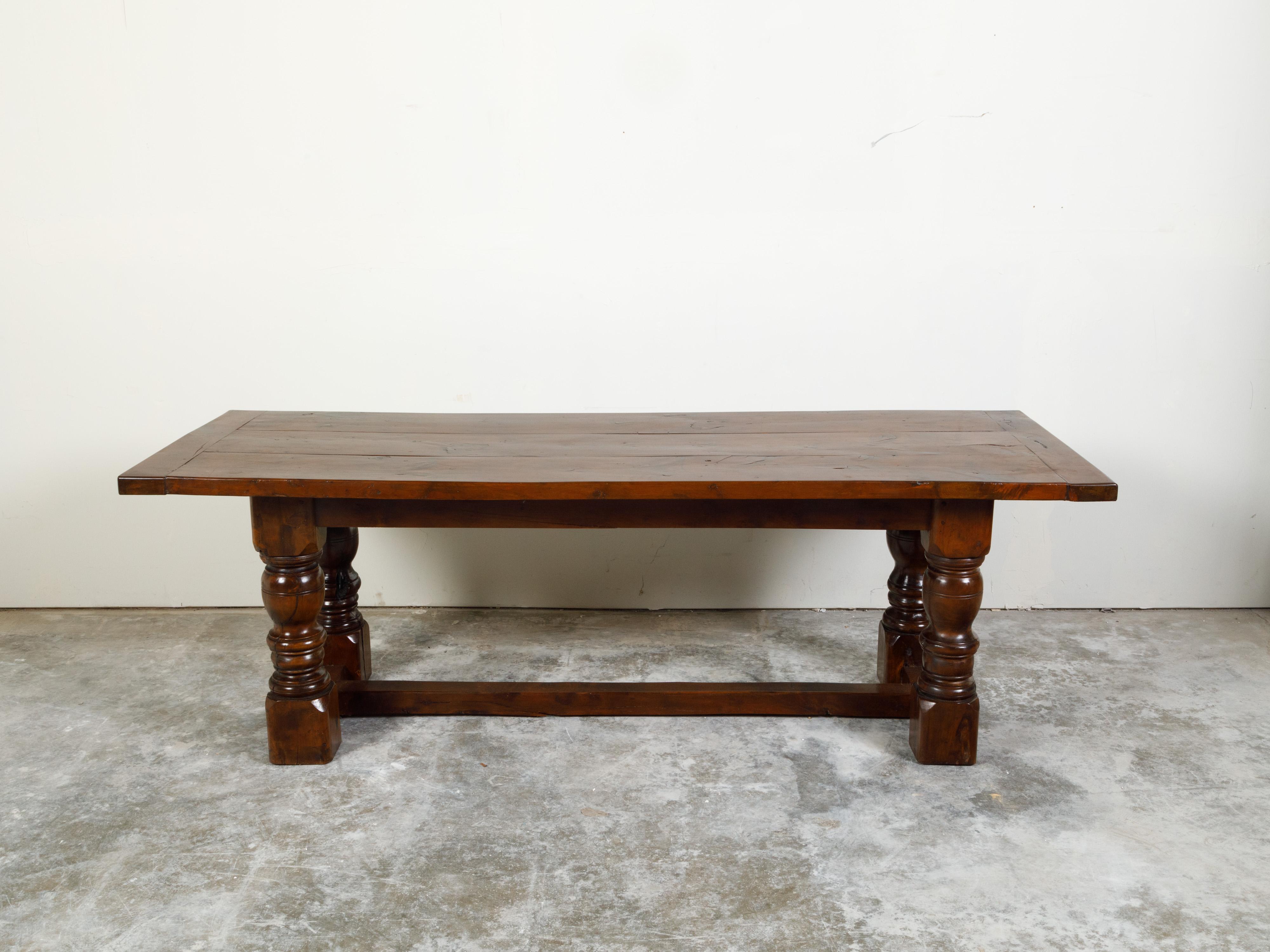 An English walnut dining table from the 19th century, with turned legs and H-Form cross stretcher. Created in England during the 19th century, this walnut table features a rectangular planked top sitting above four turned legs connected to one