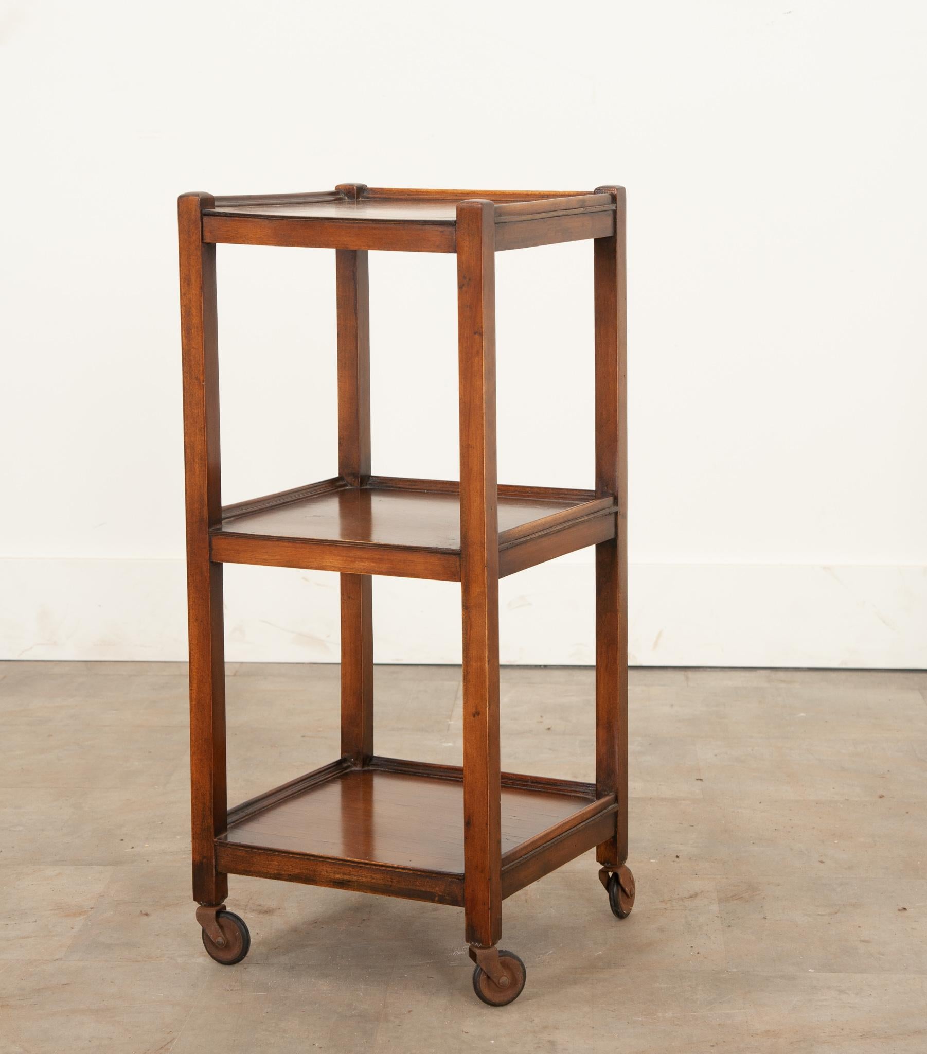 A darling petite etagere from England, crafted during the 1800’s from solid walnut. Three tiers each have a three-quarter gallery connected to square upright supports. Featuring its original casters, it has the ability to turn 360 degrees. Great for