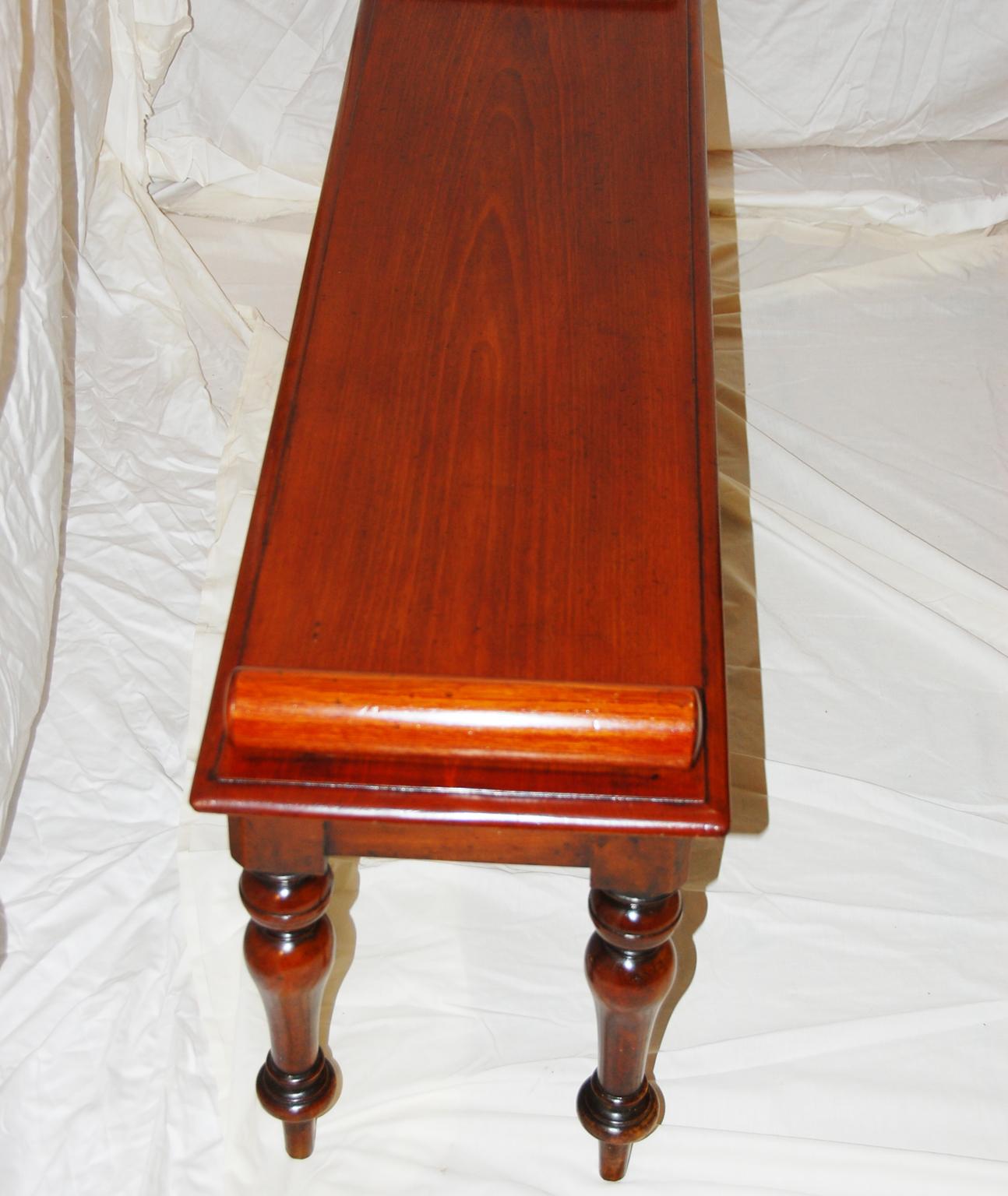 English 19th century walnut hall bench. This four foot long bench has nicely turned and tapered legs, single board seat which has two turned rolls, one at each end. These rolls not only gave a simple form more presence but also would hold a cushion