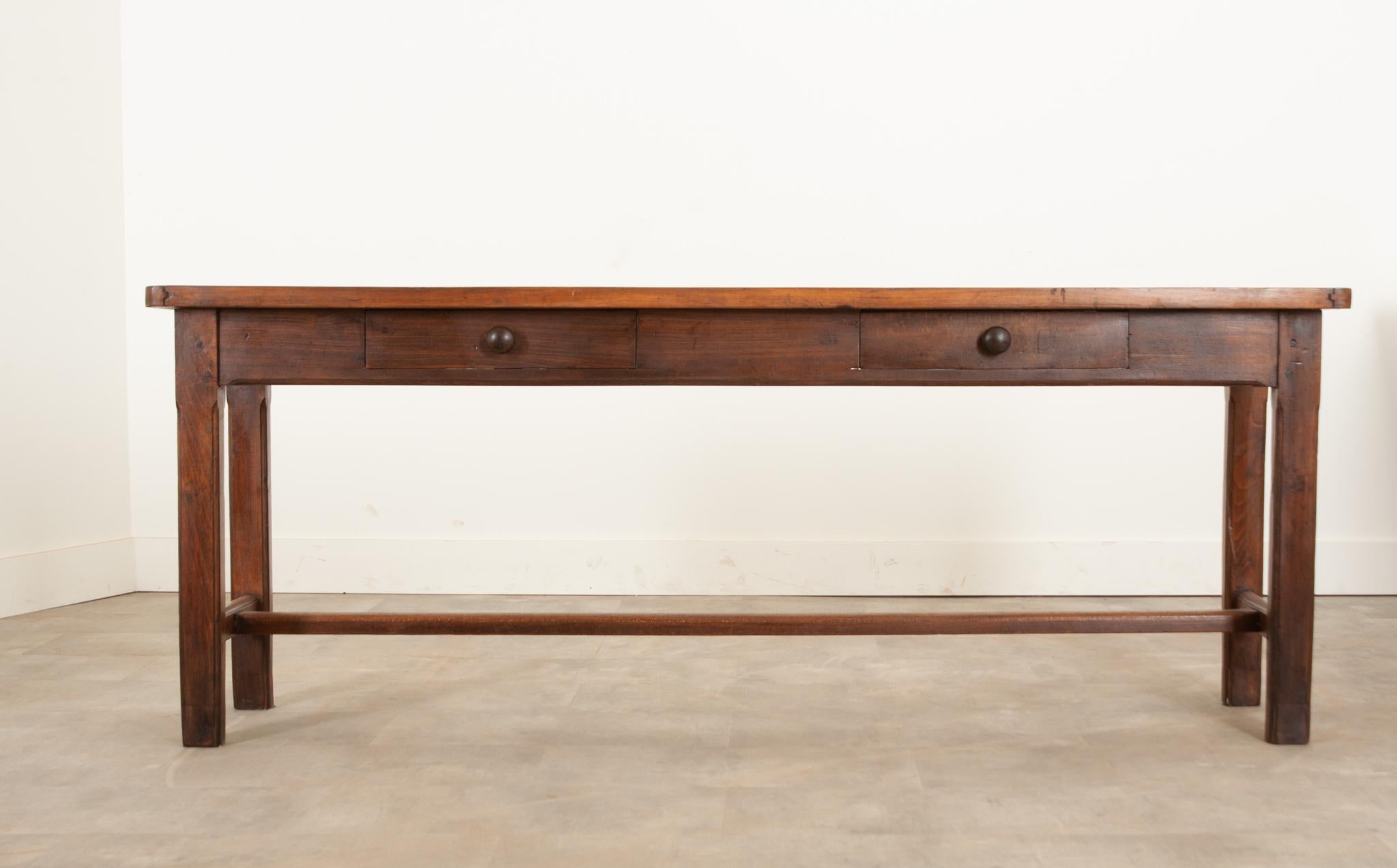 English thick walnut top server with fruitwood base. The apron houses two drawers, each fixed with a simple metal pull. Chamfered legs connect to an H shaped stretcher for continued support for everyday use. Make sure to view the detailed images to