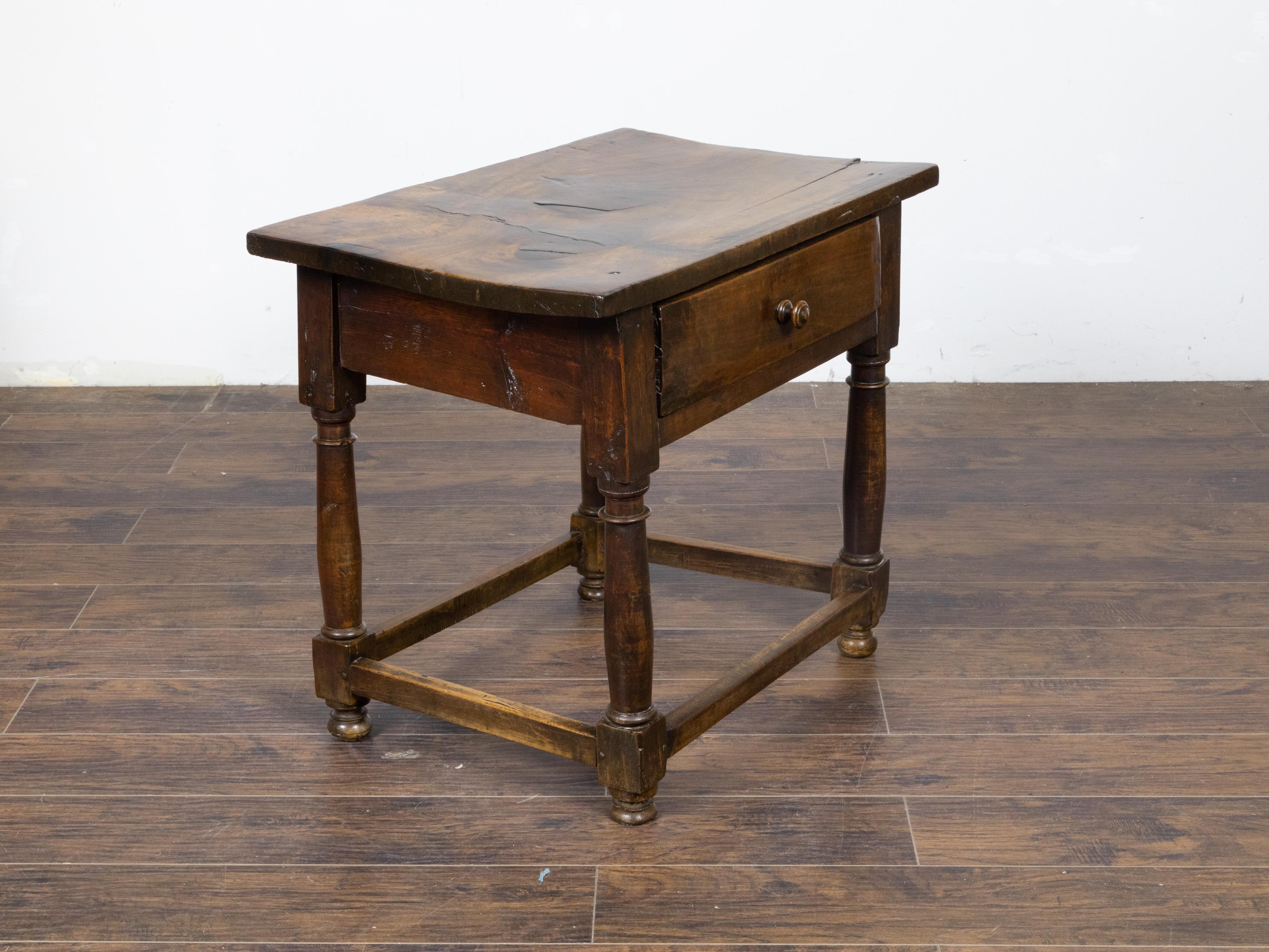 An English walnut table from the 19th century with single drawer, column-shaped legs on bun feet, plain side stretchers and nicely aged patina. This English walnut table hails from the 19th century and emanates a timeless elegance that promises to