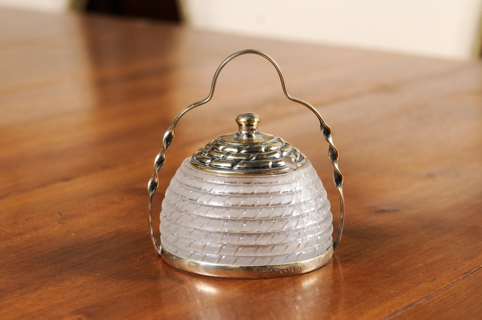 An English glass and silver lidded container from the 20th century, with twisted effects and top handle. created in England during the 20th century, this small container features a frosted glass body made of a succession of rings with angled