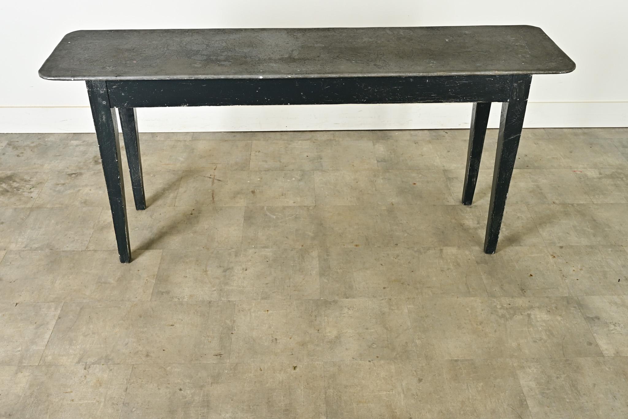 A fantastic console table or work table from England, early 20th century, featuring a zinc-plated top surface on painted wood legs. The dark gray metal sheet has wonderful texture and swirls of oxidation in matte texture, shaped to softly rounded