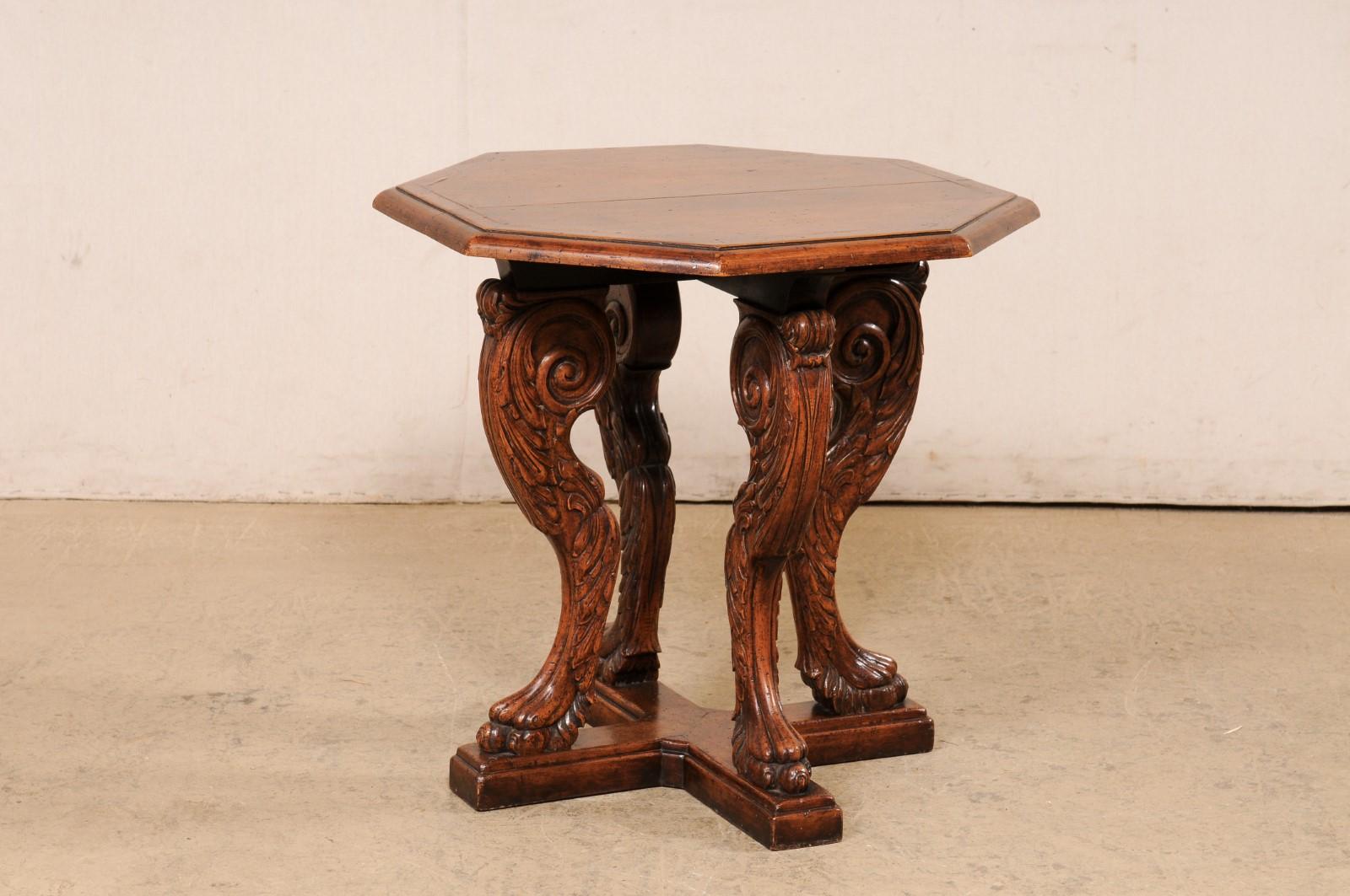 An English beautifully-carved and octagonally shaped table from the mid 20th century. This vintage gueridon-style table from England features an octagonal top which is raised upon four ornately carved legs (three-dimensionally) in the likeliness of