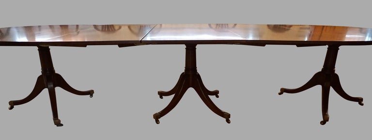 A good English Georgian style 3 pedestal mahogany dining table retaining its 2 original leaves, the center pedestal of quadripartite form, the ends of tripartite form. This versatile table can be used as a 2 pedestal table with no leaves or one