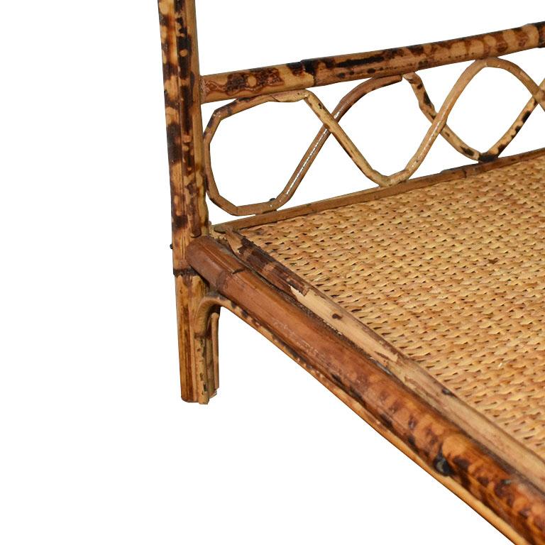 A small burnt bamboo or tortoise bamboo shelf with a woven cane top. This shelf features three tiers and is decorated at the back of each shelf with bent bamboo. This piece will make a lovely side table, nightstand or be great for extra storage in a