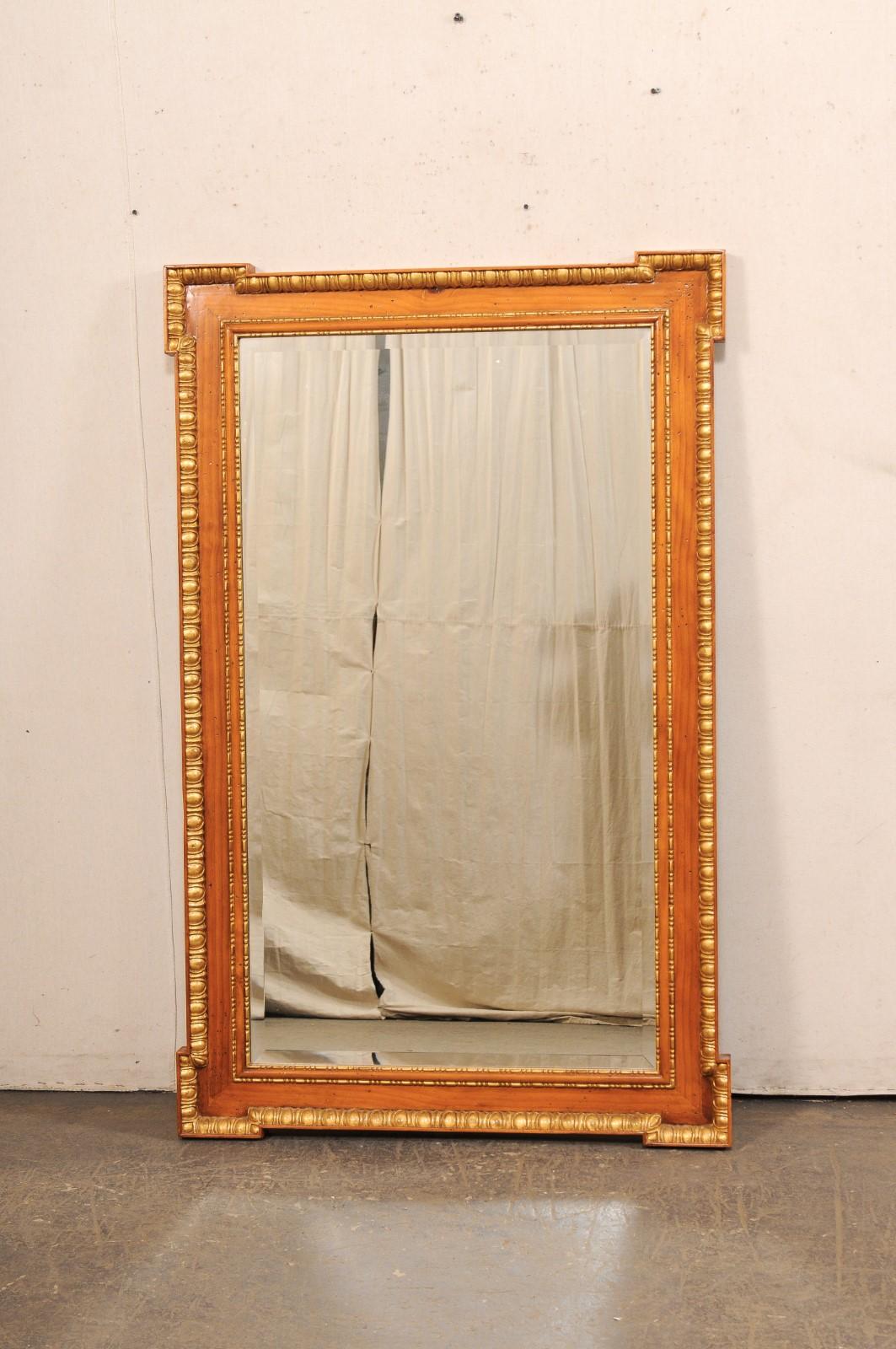 An English carved wood mirror, with nice trim and gilt accents. This vintage mirror from England has a rectangular-shape with stylized corners, which look similar to arrows pointing outward in each direction, with egg-n-dart trim outlining the