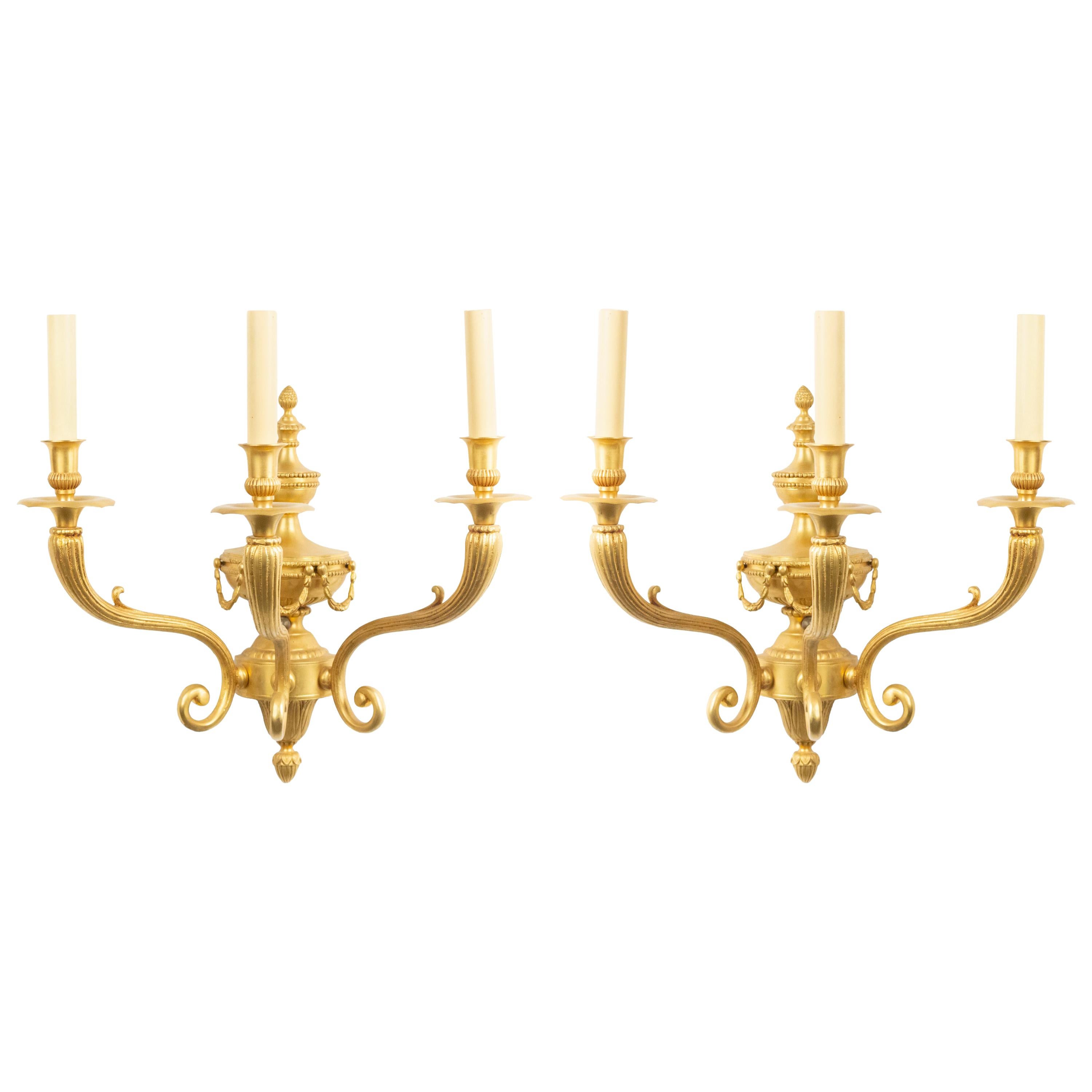 Pair of English Adam style 20th century bronze dore wall sconces with 3 fluted scroll arms, urn, and festoon design center.