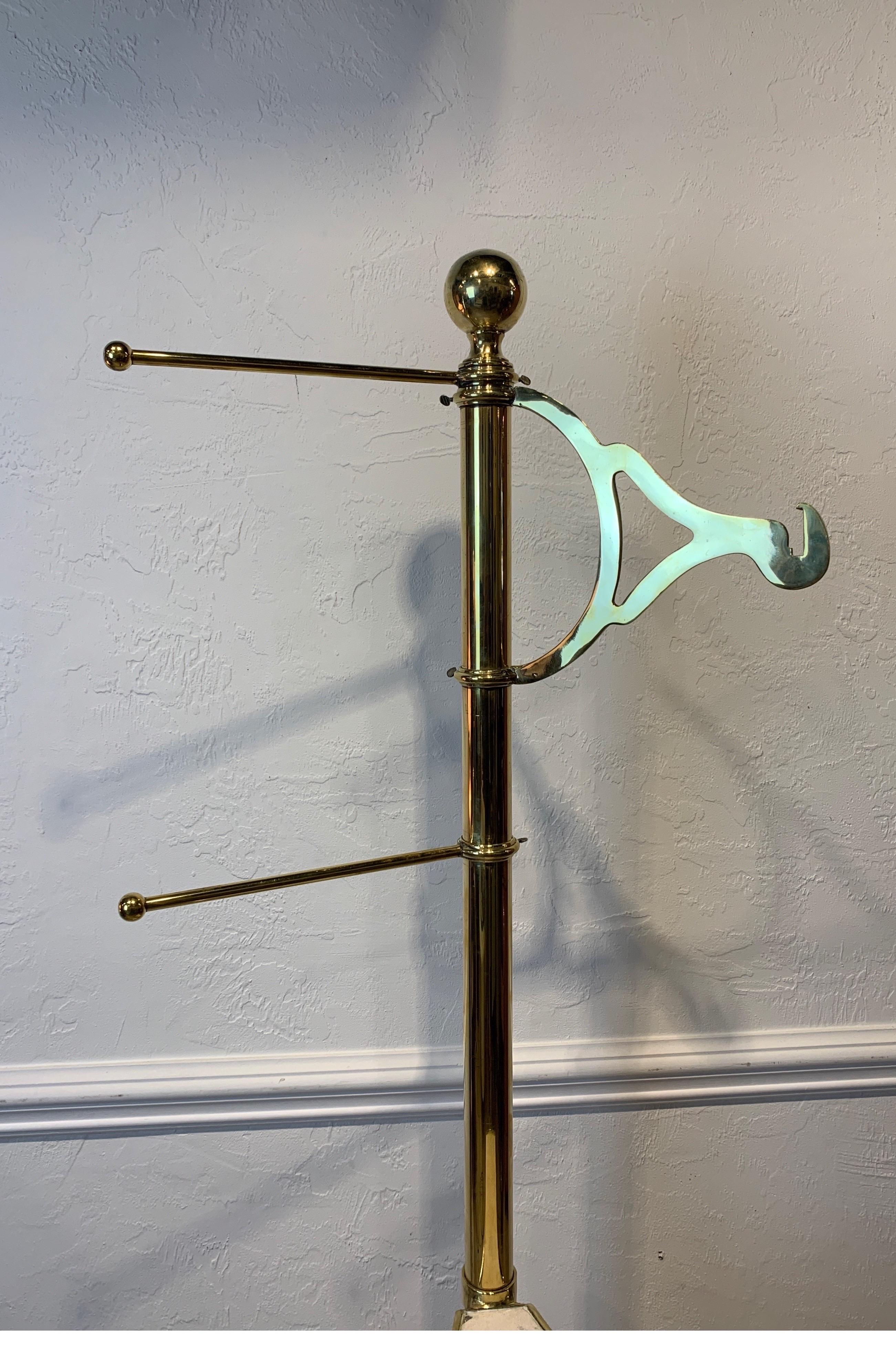 Late 19th century English polished brass clothes stand. 3 adjustable shelves with marble inserts, 2 rods and a clothes hanger.