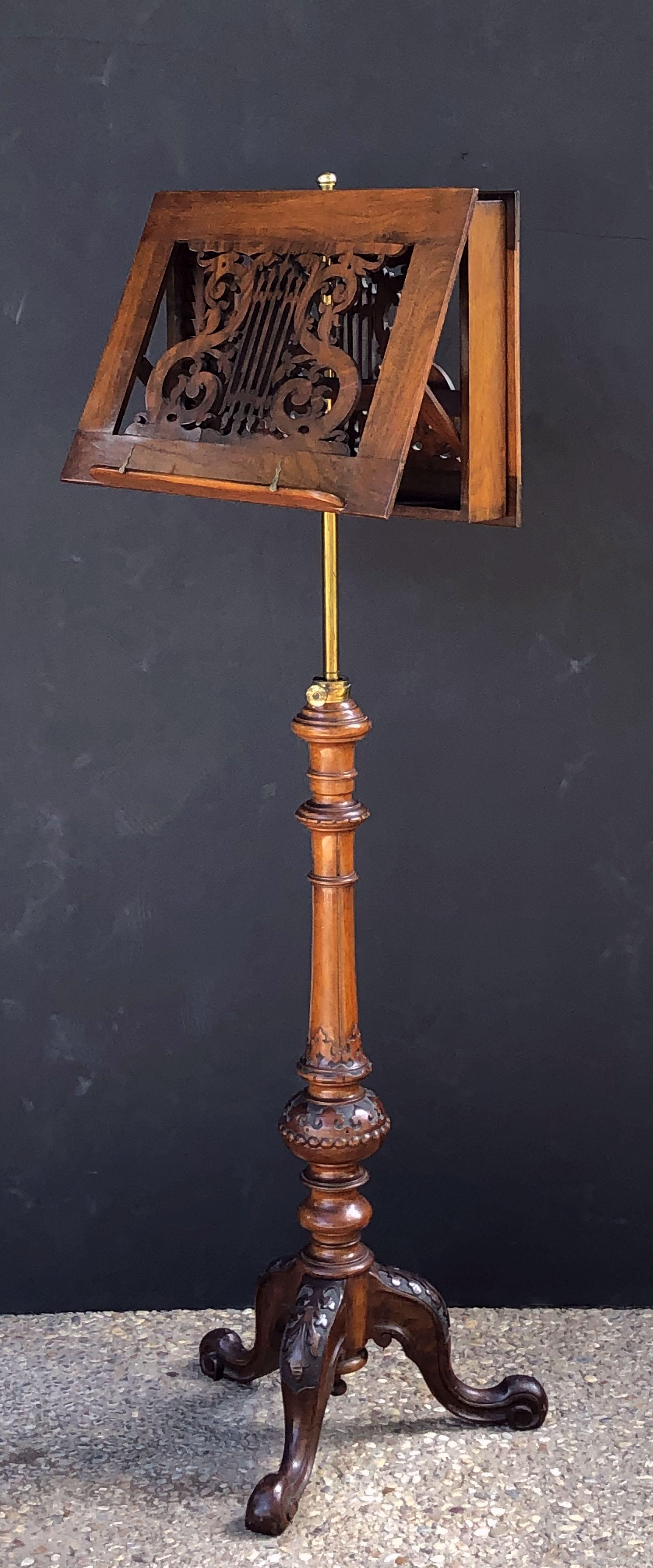 A handsome adjustable English duet (or two-sided) music stand of carved figured walnut, featuring a two sided stand with a lyre design attached to a brass rod, mounted to a tripod base with carved cabriole legs with an acanthus leaf design.