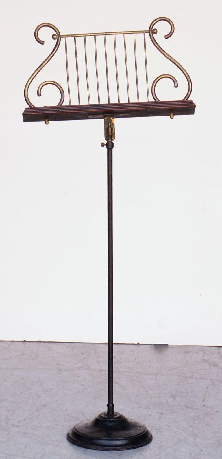 A handsome English music stand from the Edwardian Era, featuring a lyre-shaped folio easel of tubular brass and turned wood, mounted to a tubular stand allowing for adjustable heights and set upon a round iron stand.

Fully retracted height: 39