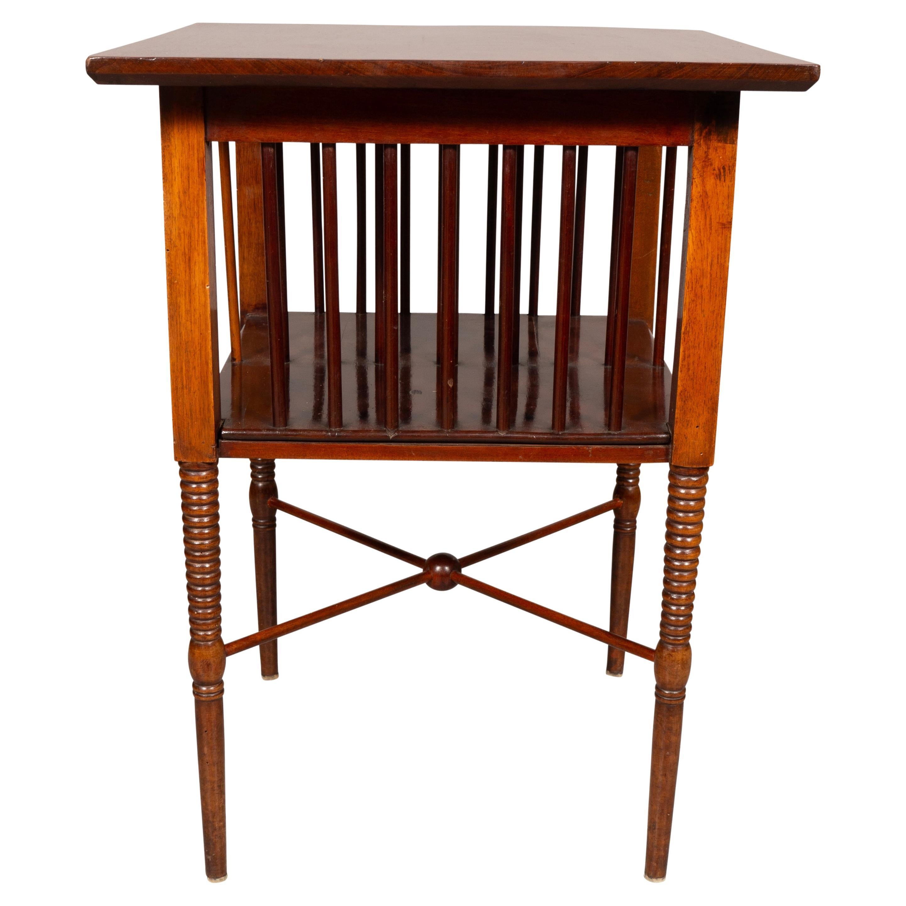 Square solid mahogany top over spindle sides supporting a conforming shelf. Circular ring turned legs joined by an X form stretcher with central ball turning.