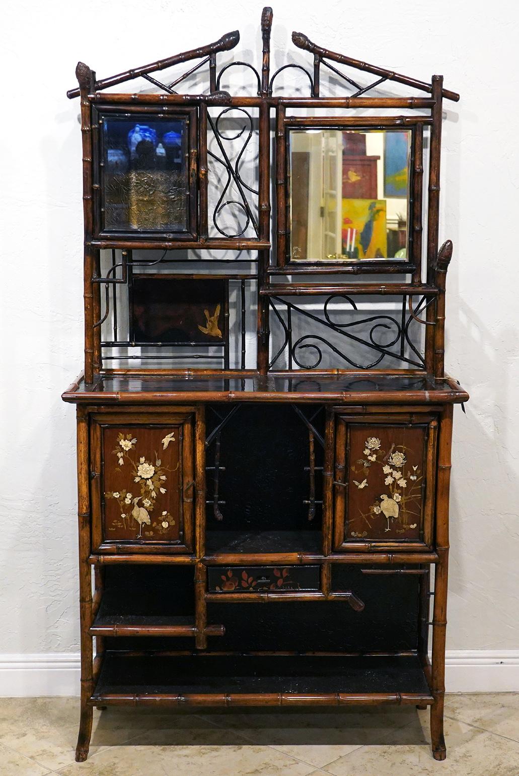 A very good English Aesthetic Movement bamboo and lacquer cabinet etagere having an openwork architectural pediment above a beveled glass door cabinet flanked by a beveled mirror plate. The lower deeper section with rectangular top and lacquered