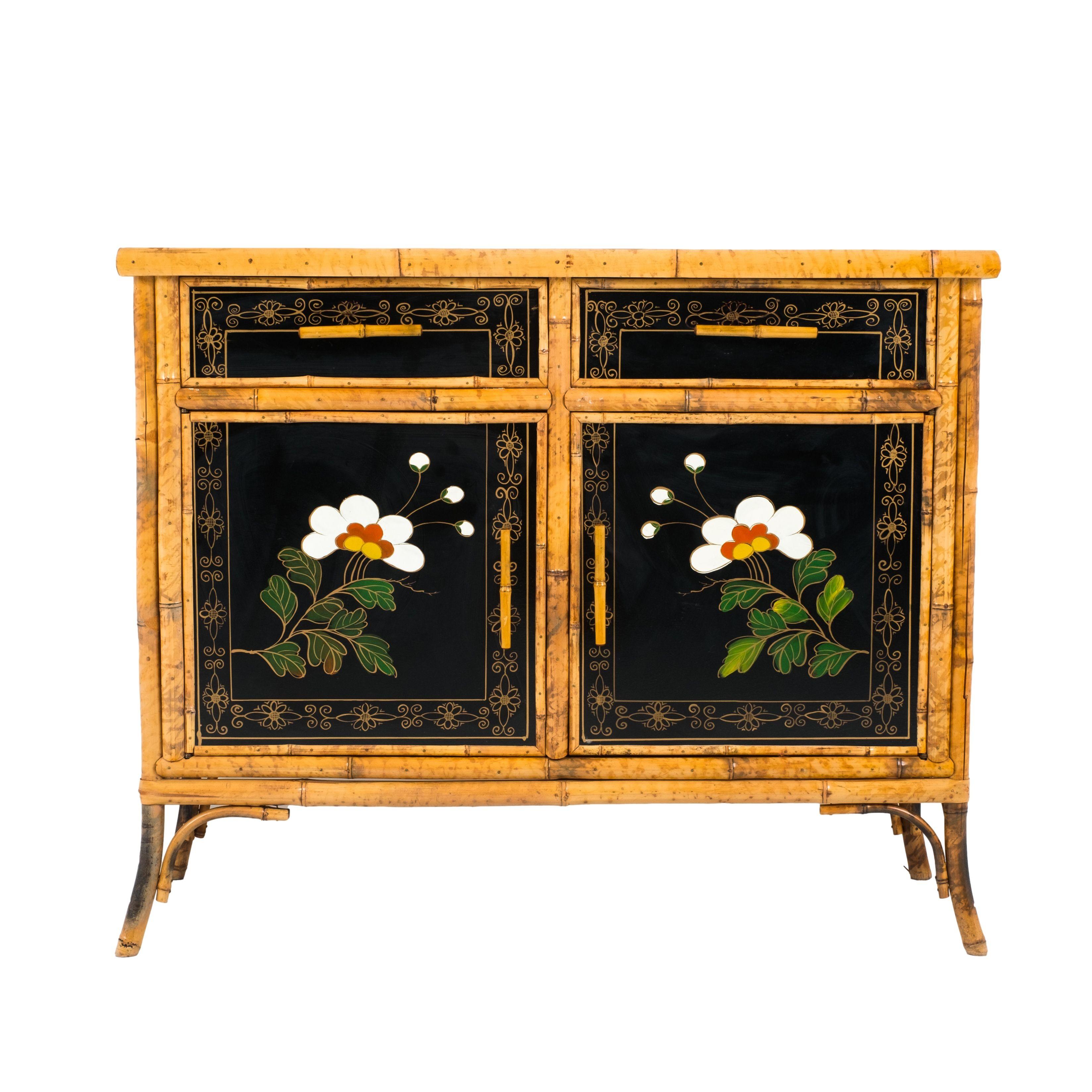 English bamboo framed black leather topped cabinet in the Anglo-Japanese Aesthetic Movement taste. The cabinet features floral painted decorations on the black lacquered paper side panels, as well as on the faces of two shallow drawers over two wood