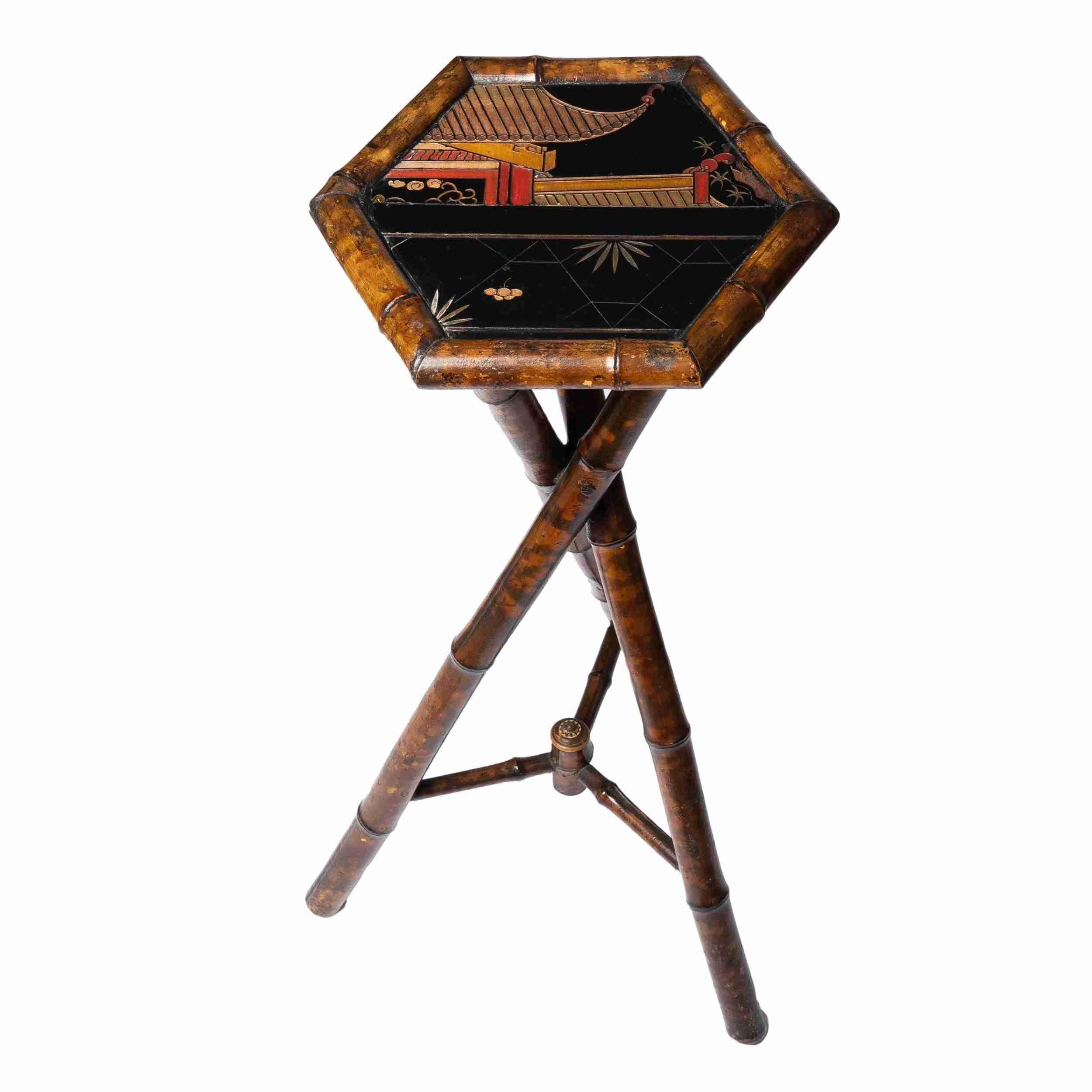 English Aesthetic Movement bamboo tripod plant stand with a painted low relief graphic carving on top. The top of the stand features a geometric pattern with floral shapes on the bottom half and a truncated view of a red and yellow painted Asian