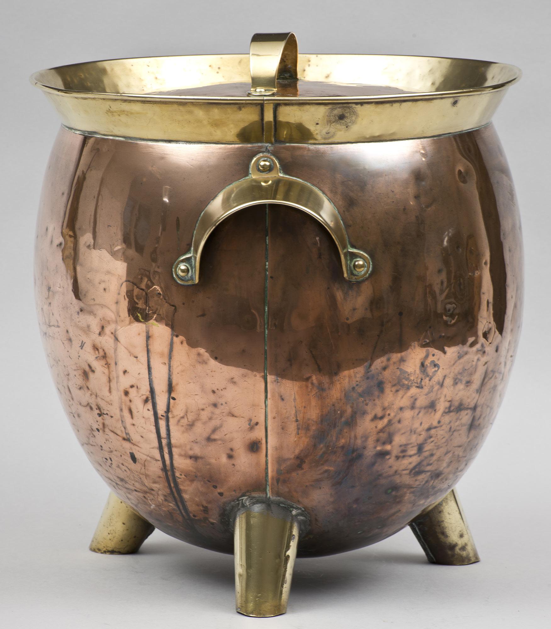 Aesthetic Movement hand-hammered copper coal scuttle with brass handles, three brass feet and rim in a circular design attributed to Christopher Dresser.