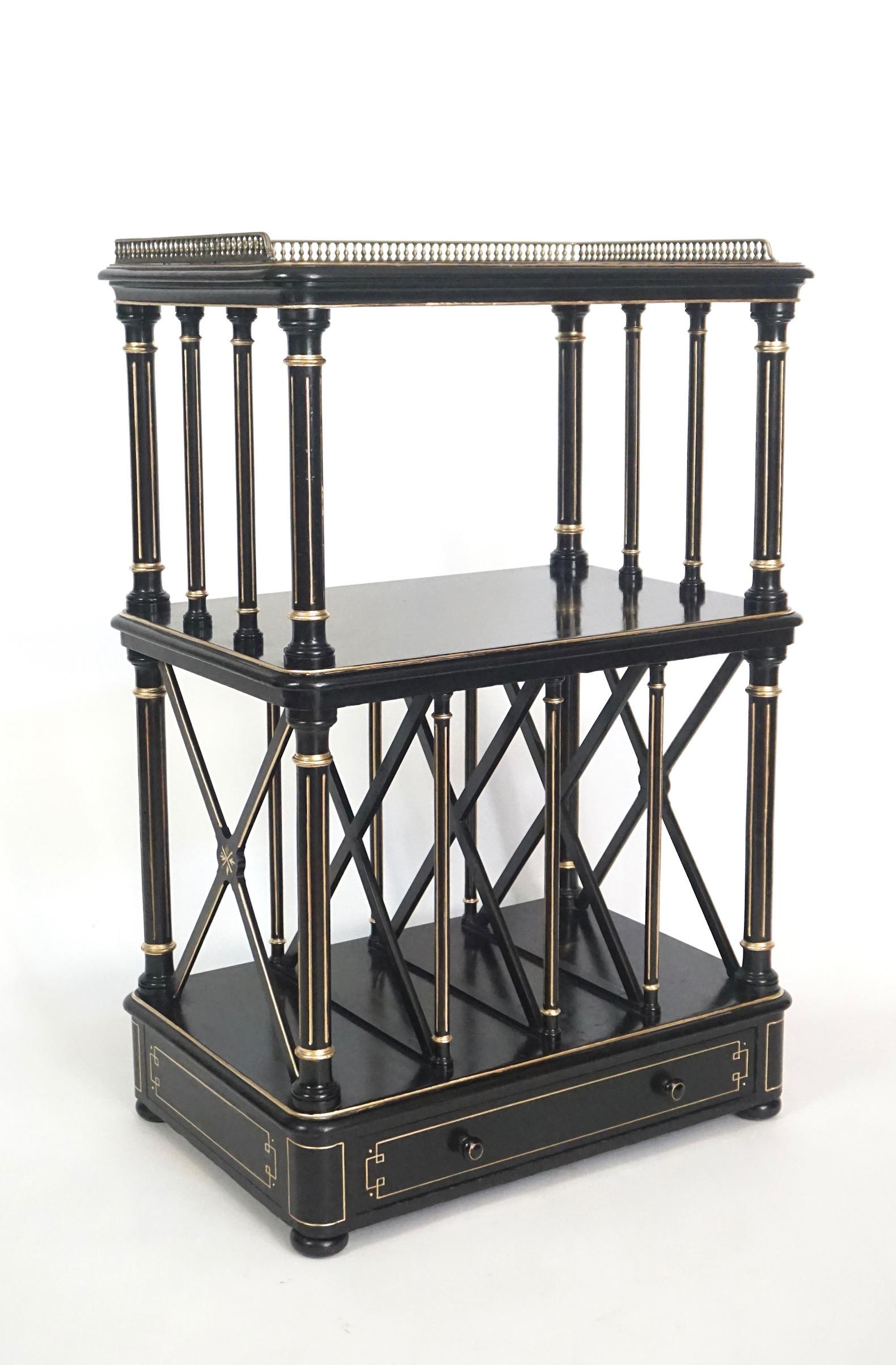 A chic circa 1875 English Aesthetic Movement period ebonized and parcel gilt étagère of three tier form, the top shelf with brass 'baluster' gallery above fluted colonette supported second open tier and lower 'Canterbury' tier with X-form dividers