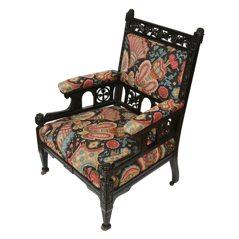 English Aesthetic movement ebonized armchair with vibrant colored needlepoint fabric seat, armrests and back. Legs on casters.