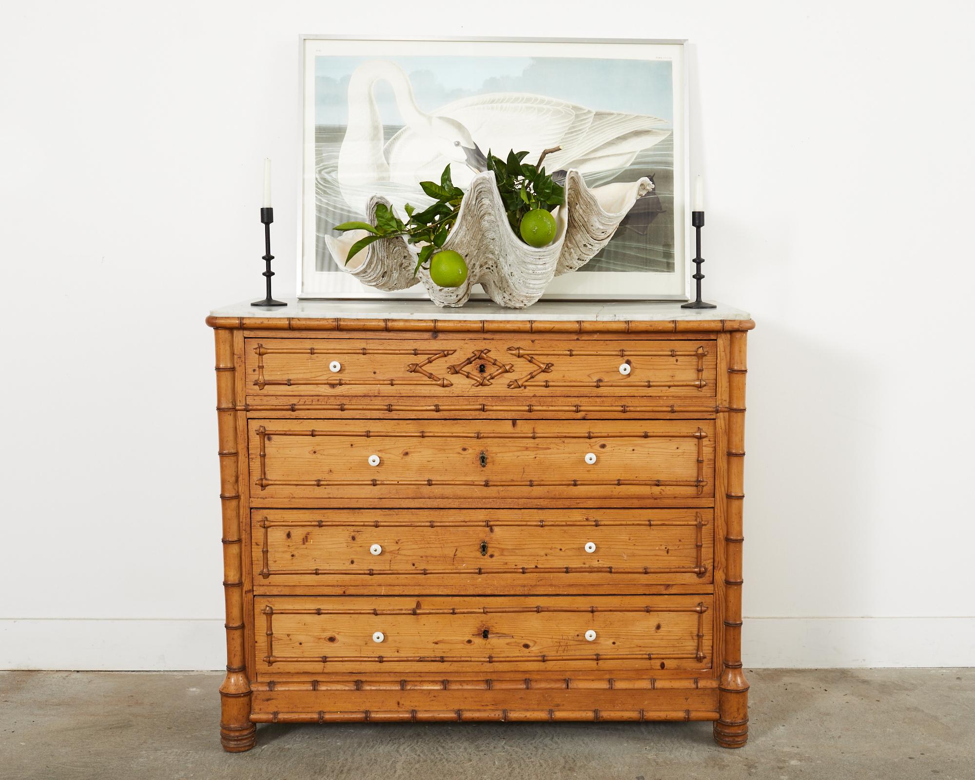 Grand 19th century English Aesthetic movement faux bamboo pine chest featuring a Carrara marble top. The large commode measures 48 inches wide and 40 inches high. The case is fitted with four storage drawers having white porcelain pulls. Beautifully