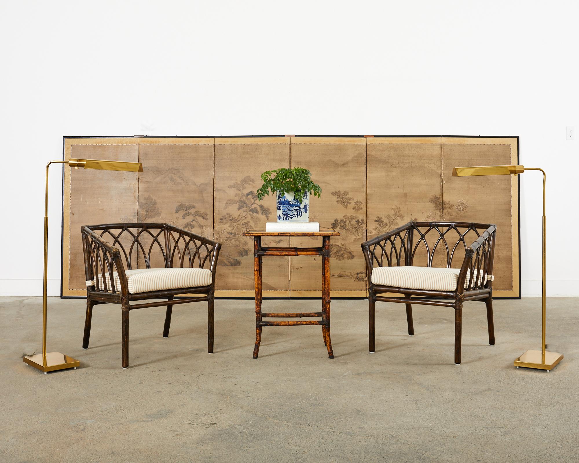 Weathered English aesthetic drink table or side table crafted from tortoise shell style bamboo poles. The table features a lacquered top with a faded Asian motif decoration. The table is supported by bamboo poles conjoined by patinated metal joints.