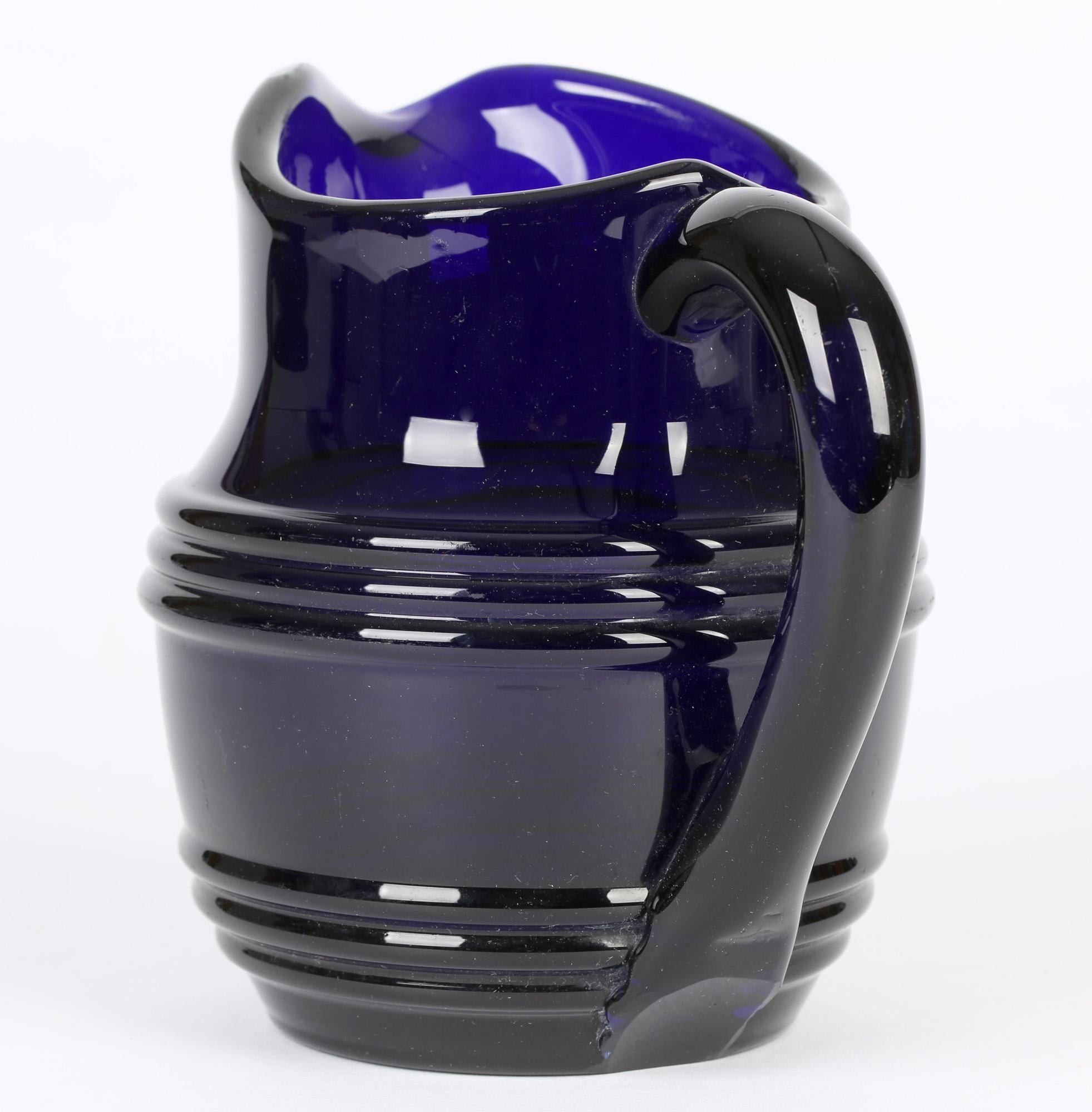 A substantial and well made antique English hand blown Bristol blue (cobalt) glass water jug or pitcher dating from around 1820/30. The heavily made jug has a squat rounded body with raised molded ribbing and with a thick loop handle applied to the