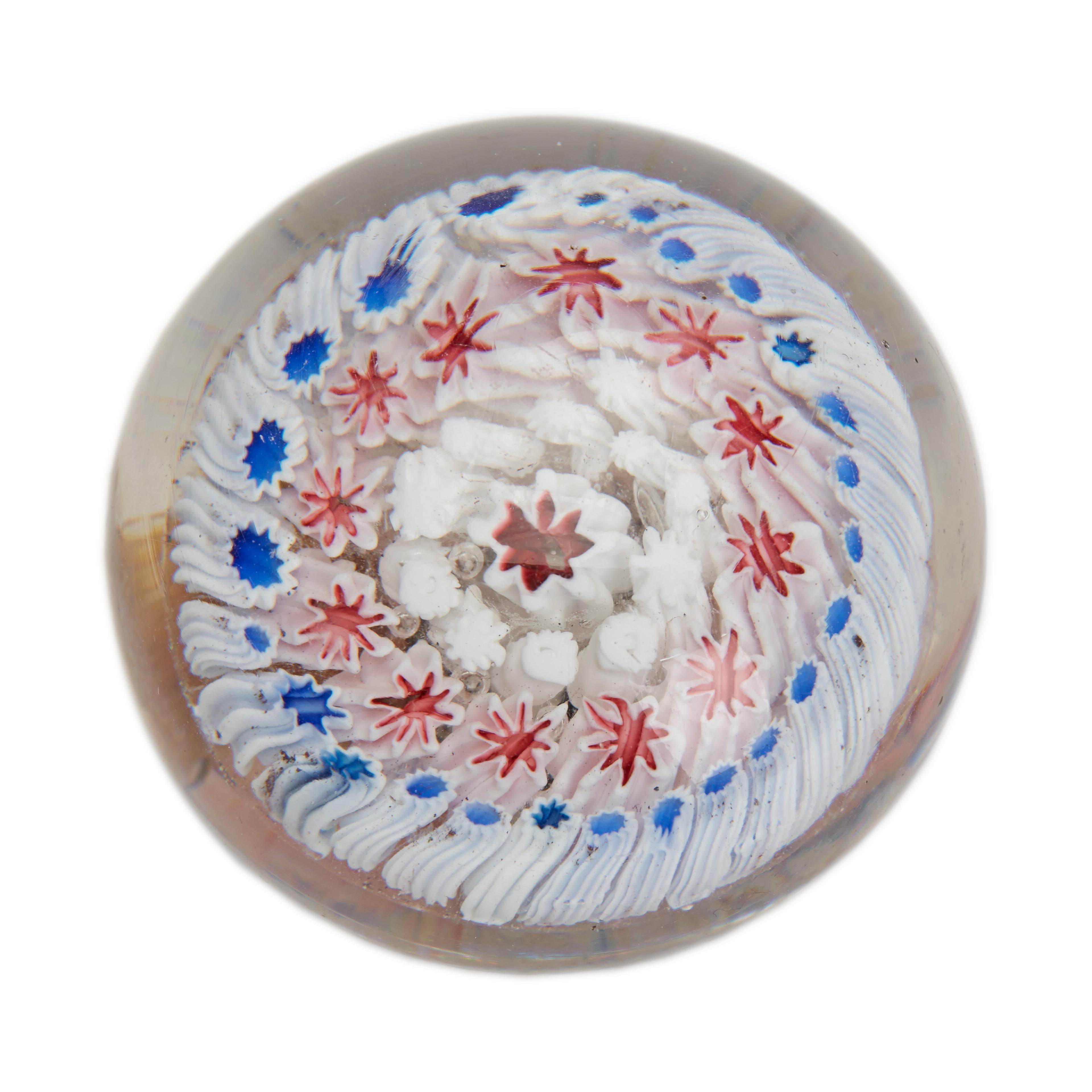A fine antique English glass concentric paperweight with rows of star formed canes probably dating from the latter 19th century. The rounded clear glass formed weight is of domed form and contains concentric rows of blue, red and white star shaped