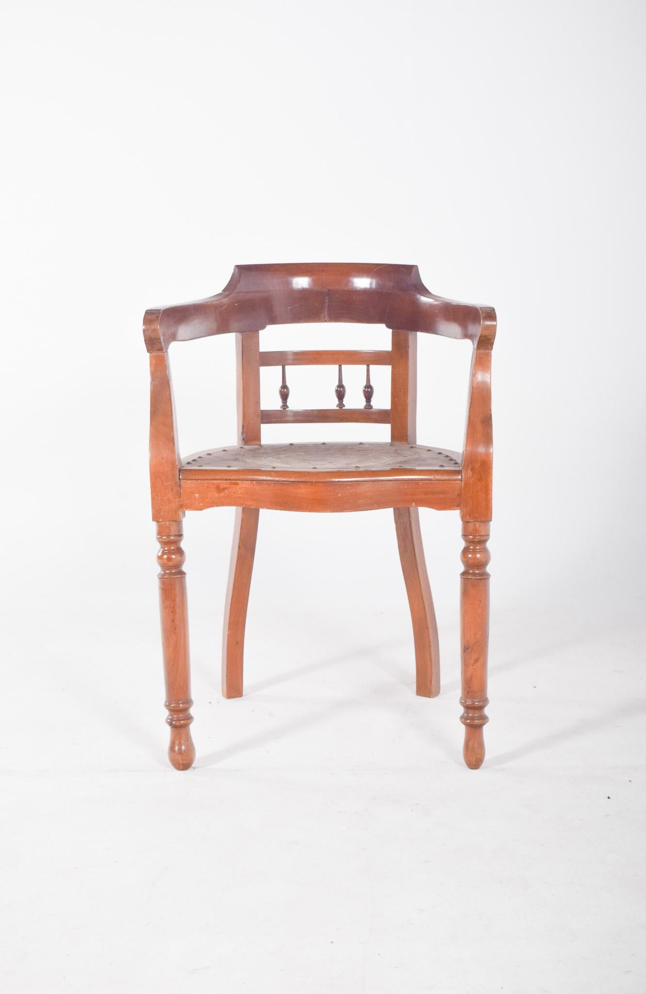 Chaise de bureau ancienne. Le dossier est incurvé et se prolonge jusqu'aux accoudoirs, formant ainsi une pièce continue. Le dossier est bas et enveloppant, avec une finition lisse et des détails discrets de balustres verticaux. Le siège est fixe, en