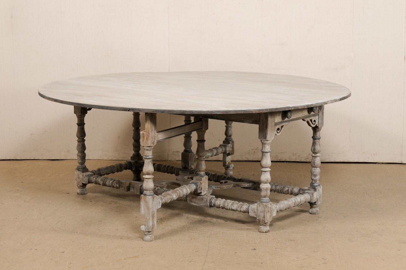 Une table anglaise de forme ronde à double pied de porte, avec tiroir, du début du XXe siècle. Cette table ancienne d'Angleterre présente un grand plateau de forme ronde avec deux feuilles tombantes de chaque côté, qui, une fois descendues, donnent