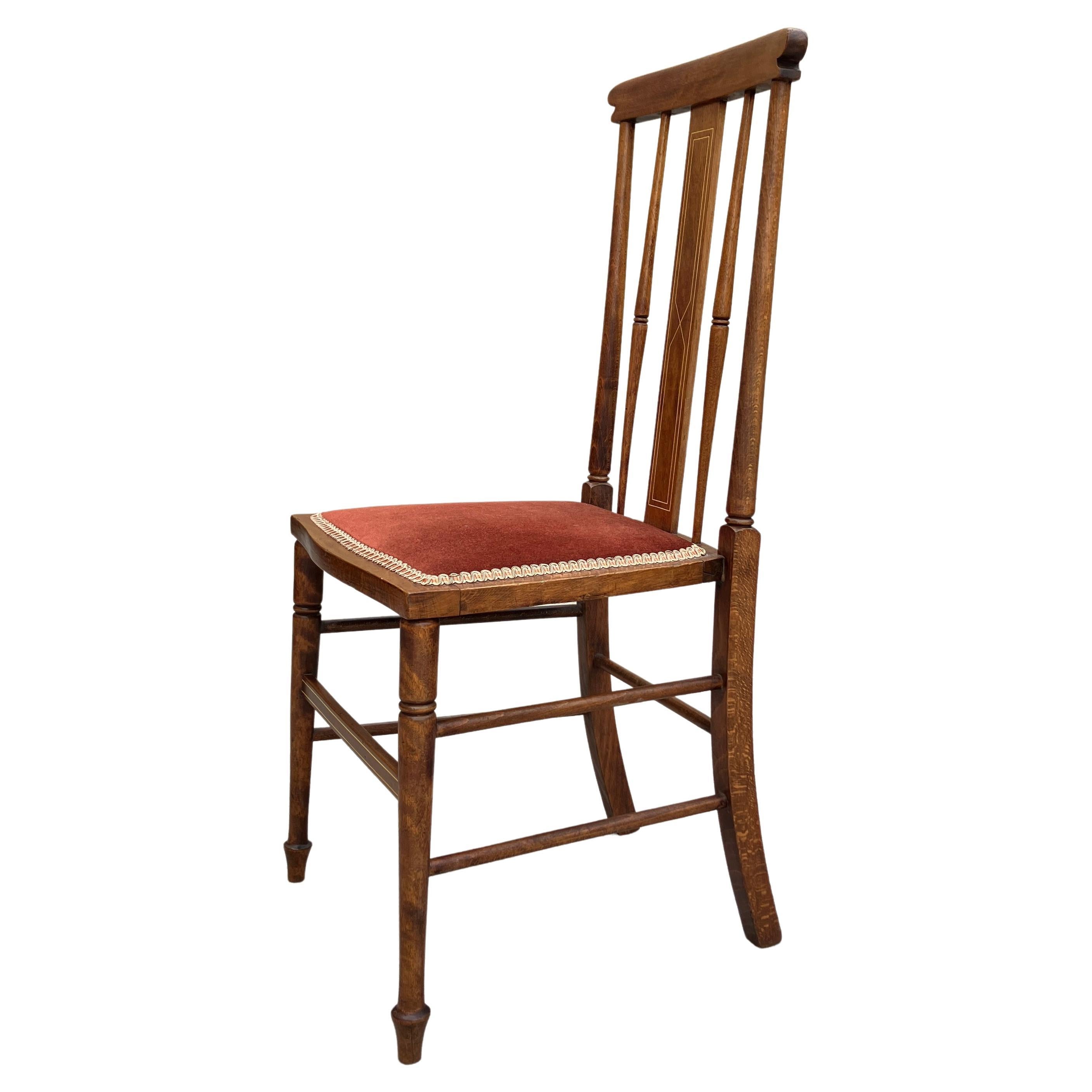 An absolutely stunning Arts & Crafts spindle back chair from the early 1900s. Made in England. The chair has delicate legs and shaped spindles on the decorative backrest. The back of the chair is tall and straight and has elegant inlay details. The