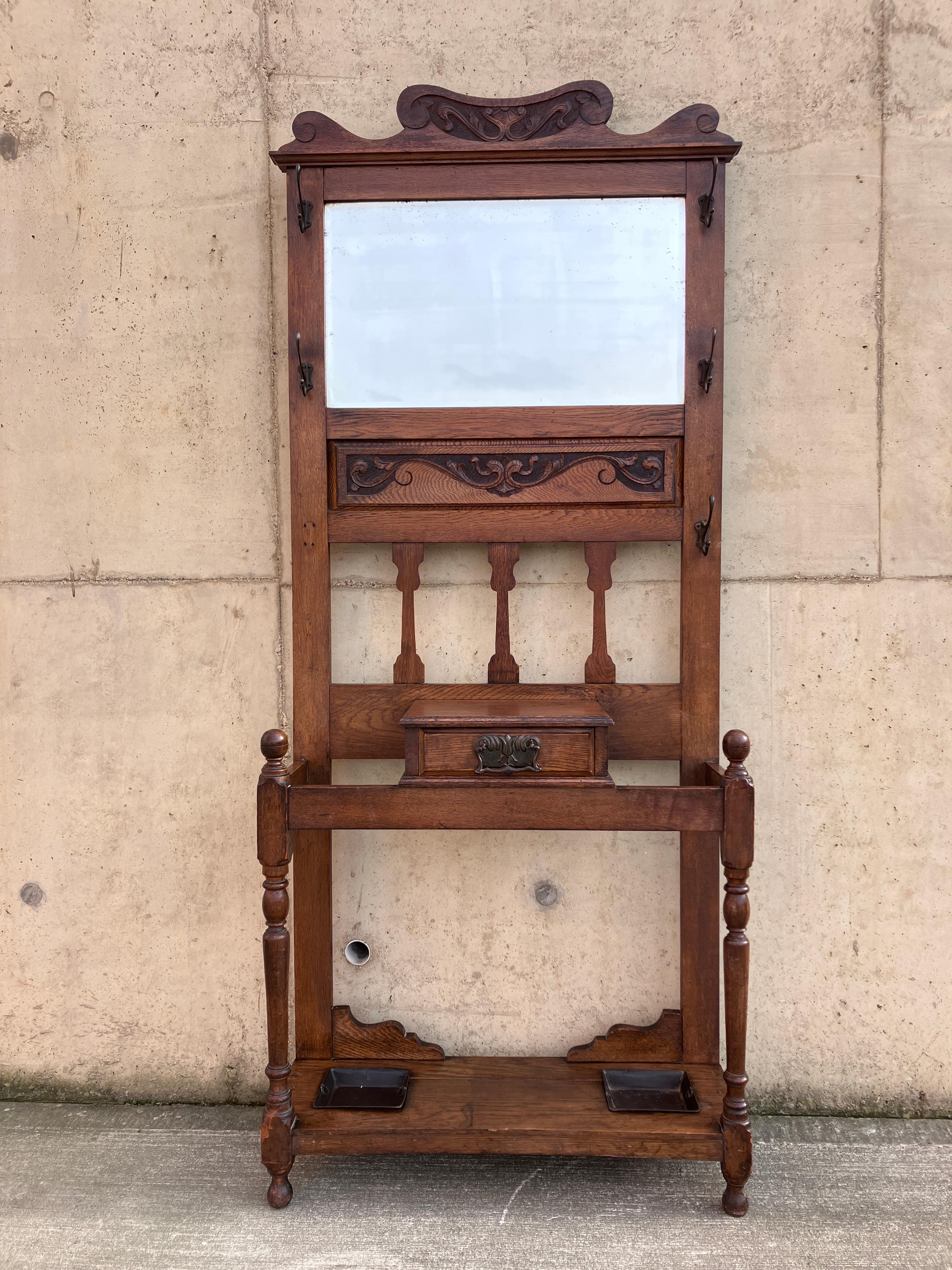 Mueble de salón antiguo inglés de caoba. El atril tiene bonitos adornos tallados en la parte posterior y elegantes patas torneadas. Hay ganchos para colgar abrigos, un cajón para objetos pequeños y un soporte para paraguas. En la parte superior hay