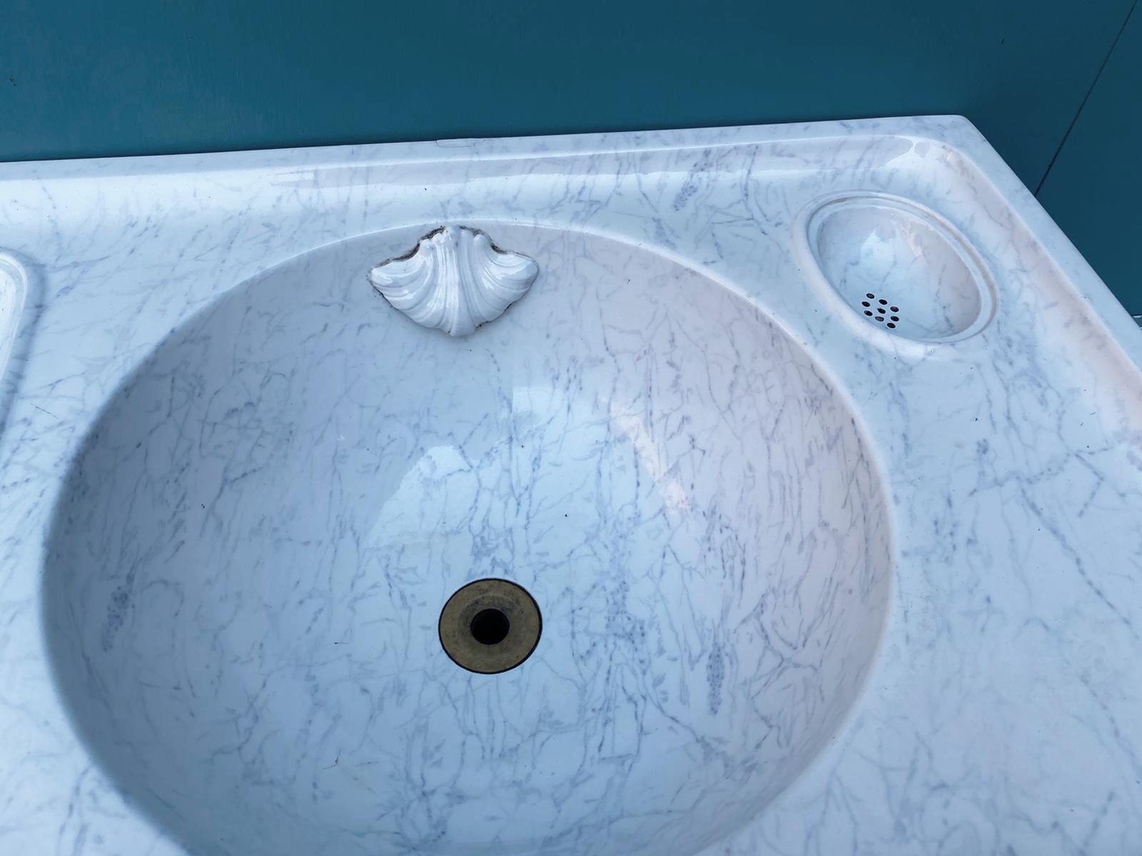 Un lavabo o lavello antico con finitura effetto marmo, dipinto a mano sotto lo smalto.