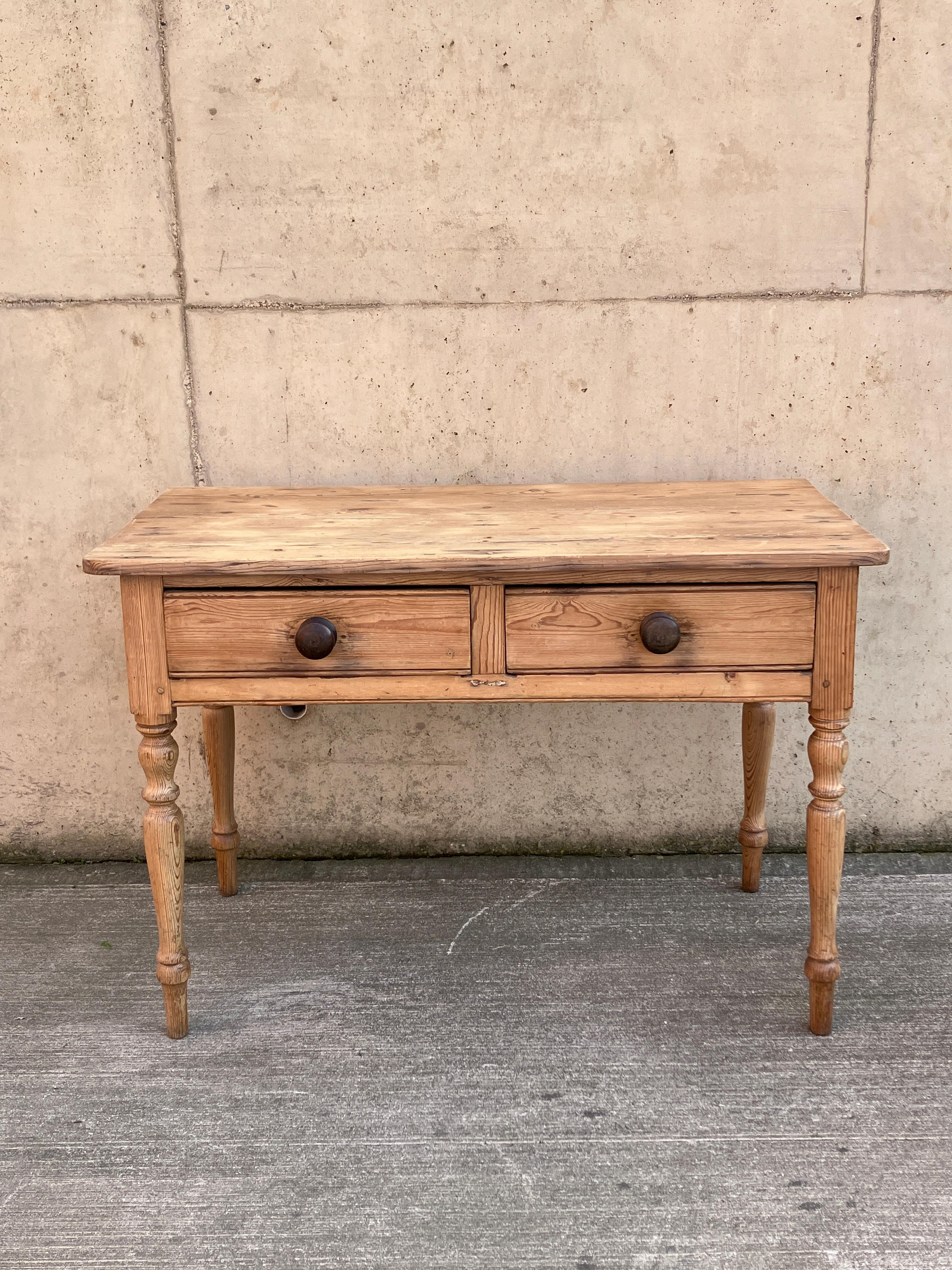 A beautiful English antique pitch pine console table with drawers. The console table has attractive slim, turned legs and beautiful dark wood knob handles on the deep drawers. An elegant size and would also work as a compact desk. 

Size overall;