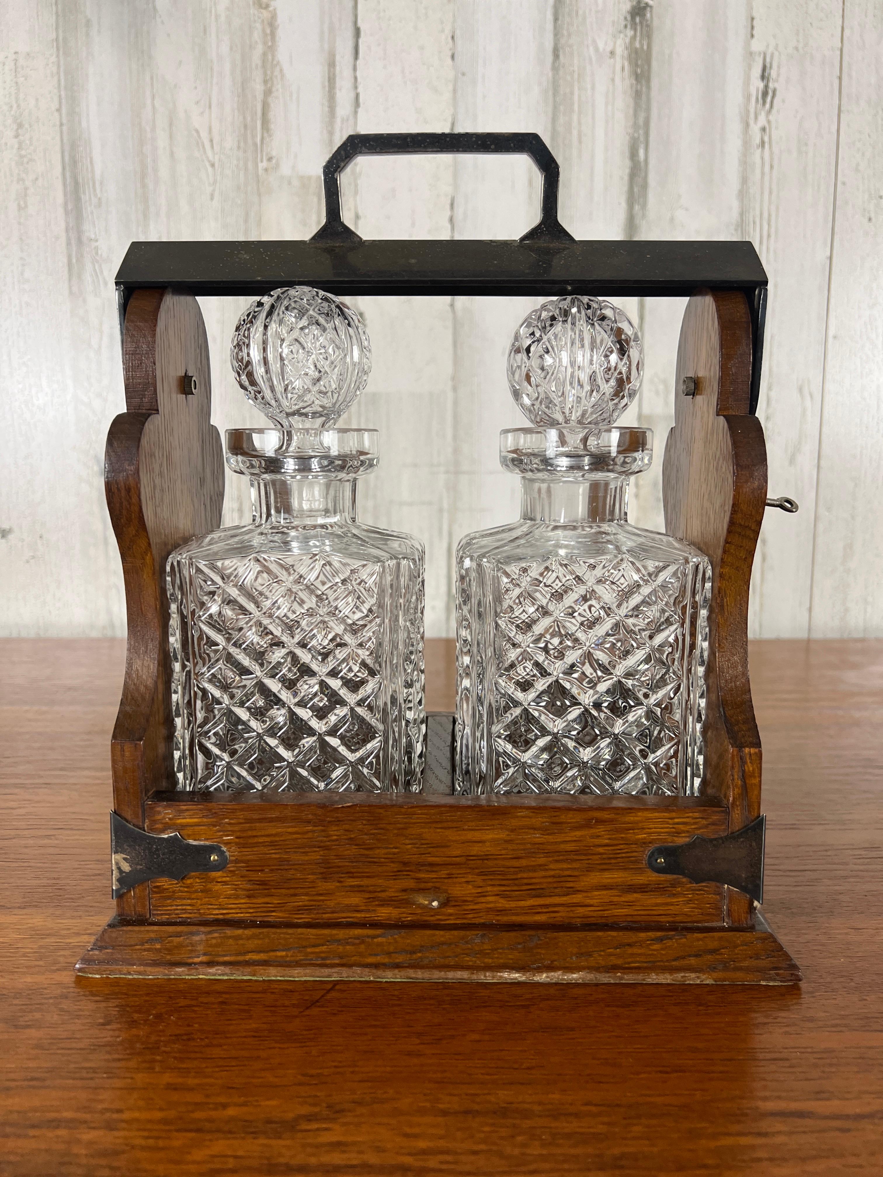 Early 20th century English Tantalus. Solid oak travel caddy with two cut glass decanters and a key for safety.