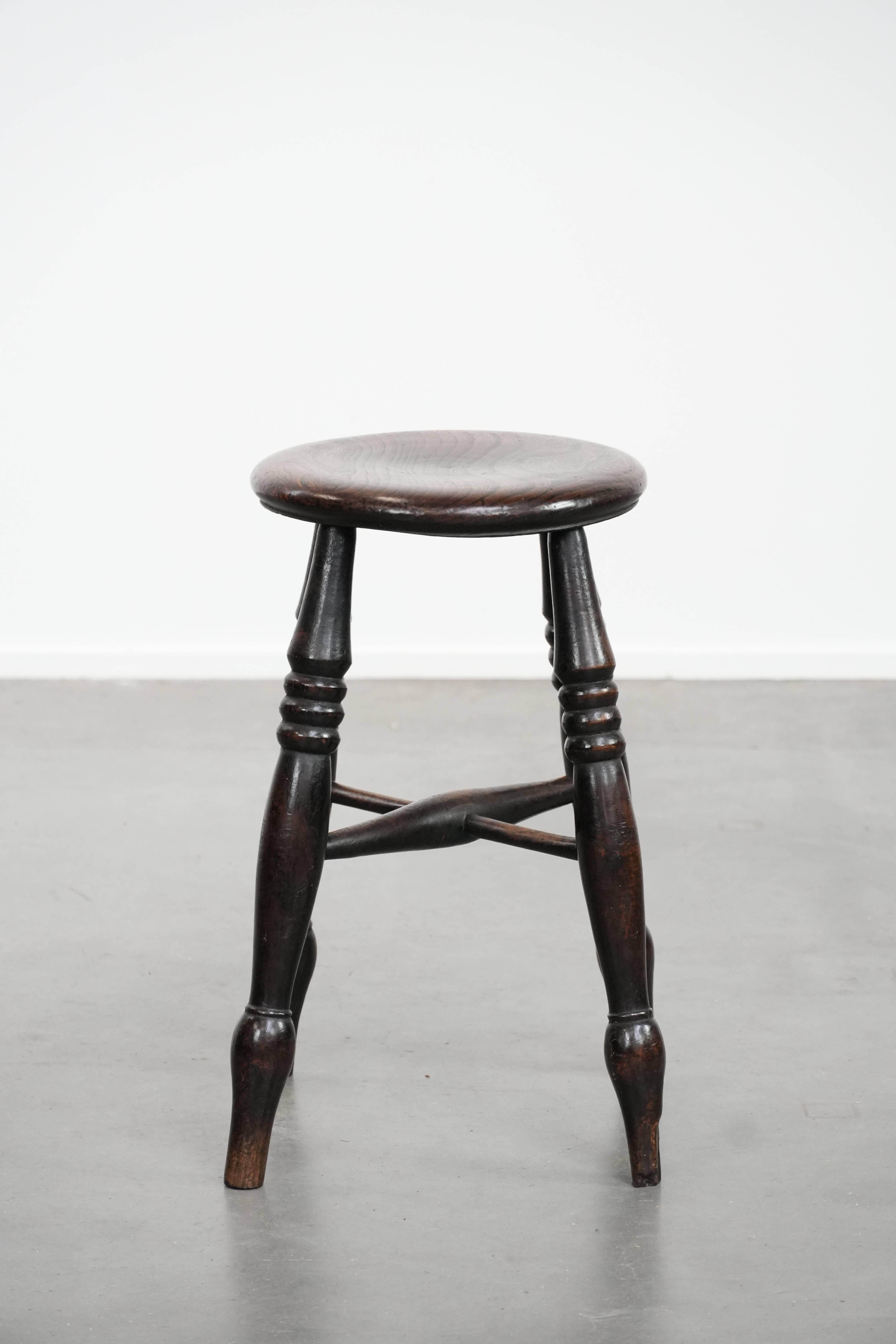 This charming and subtle antique English Windsor stool from the 18th century is an elegant addition to almost any interior. In addition to serving as a seat, it can also be easily used for decorative purposes. Due to its age and years of use, it has
