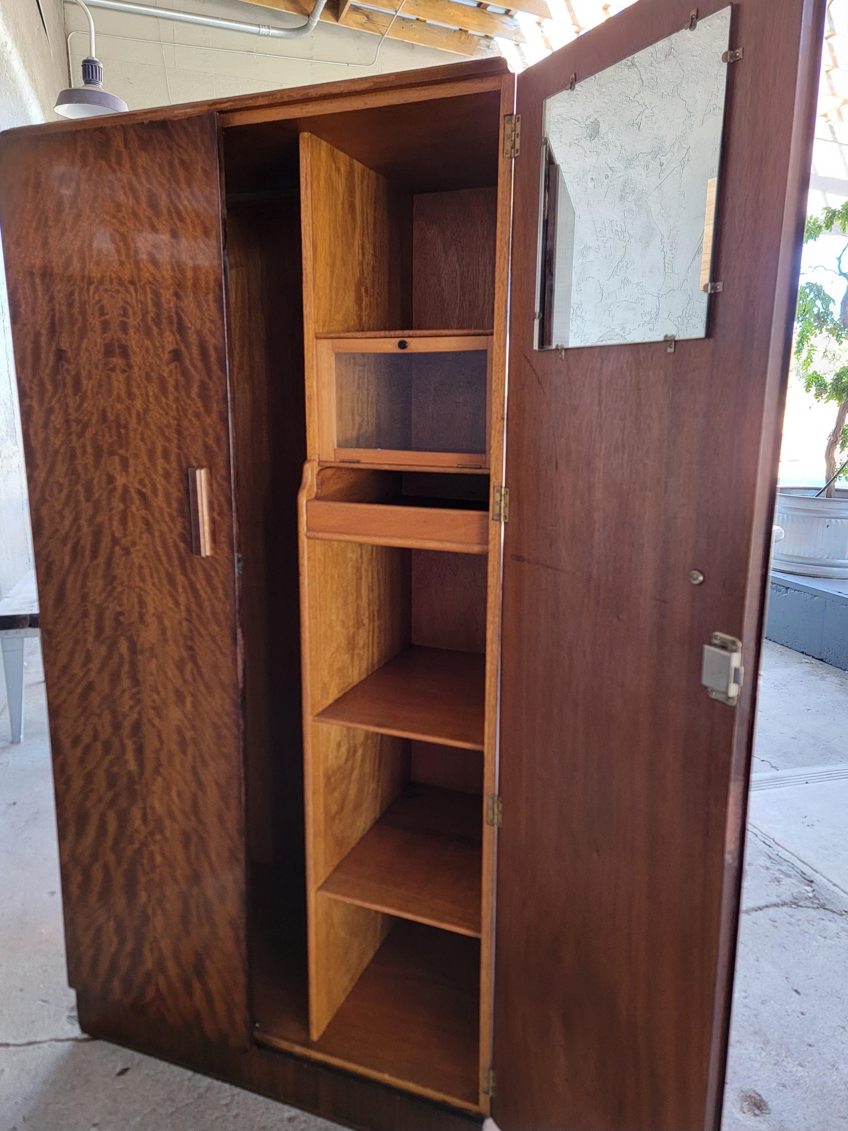 Spectacular exotic wood veneer on this Art Deco double door fitted armoire / wardrobe. Compartmentalized interior with small glass cabinet, drawer, tie hanger, clothes hanger and mirror. Retains Taunton-Weber label. Key included.

36.13 inches