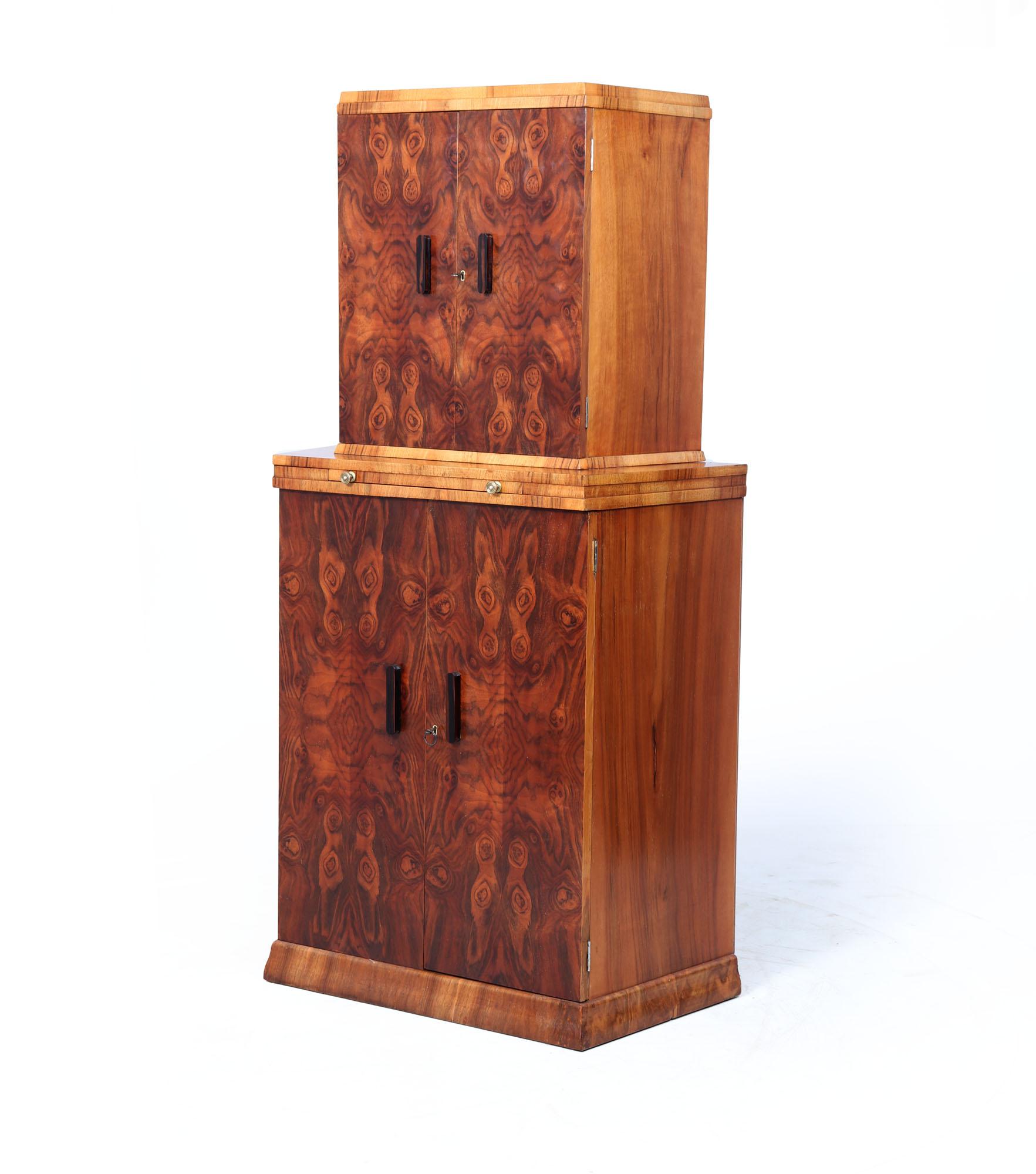 Mueble Cóctel Art Decó
Preciosa vitrina de cóctel Art Decó inglesa de los años 30, hecha a mano en nogal con rebabas y laterales y detalles de nogal en contraste. Este llamativo armario de dos niveles presenta ricas chapas de rebabas a juego con una
