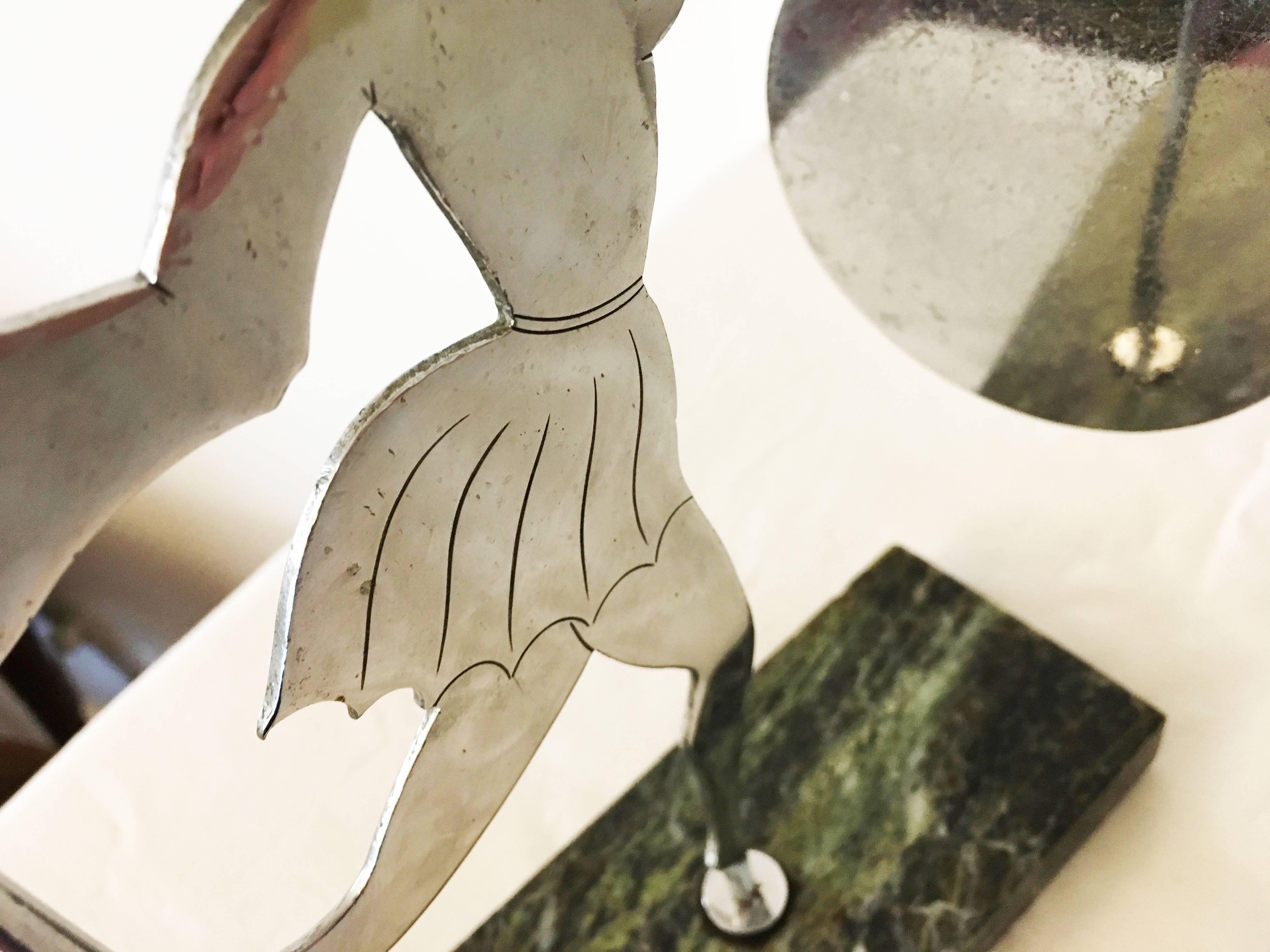 Anglais Art déco chromé Silhouette d'une femme tenant dans une main un gong en forme de disque circulaire. Dans l'autre main, elle tient le percuteur chromé à bout sphérique. La dame est debout sur un socle en marbre vert.
Le chrome est entièrement