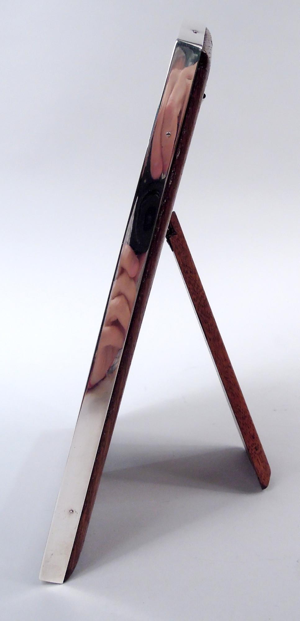 Cornice in argento sterling George V. Prodotto da Walker & Hall a Sheffield nel 1923. Finestra rettangolare nella stessa cornice con angoli superiori smussati; bordo a chiave greca su fondo foderato. Con vetro, fodera in seta, dorso in legno