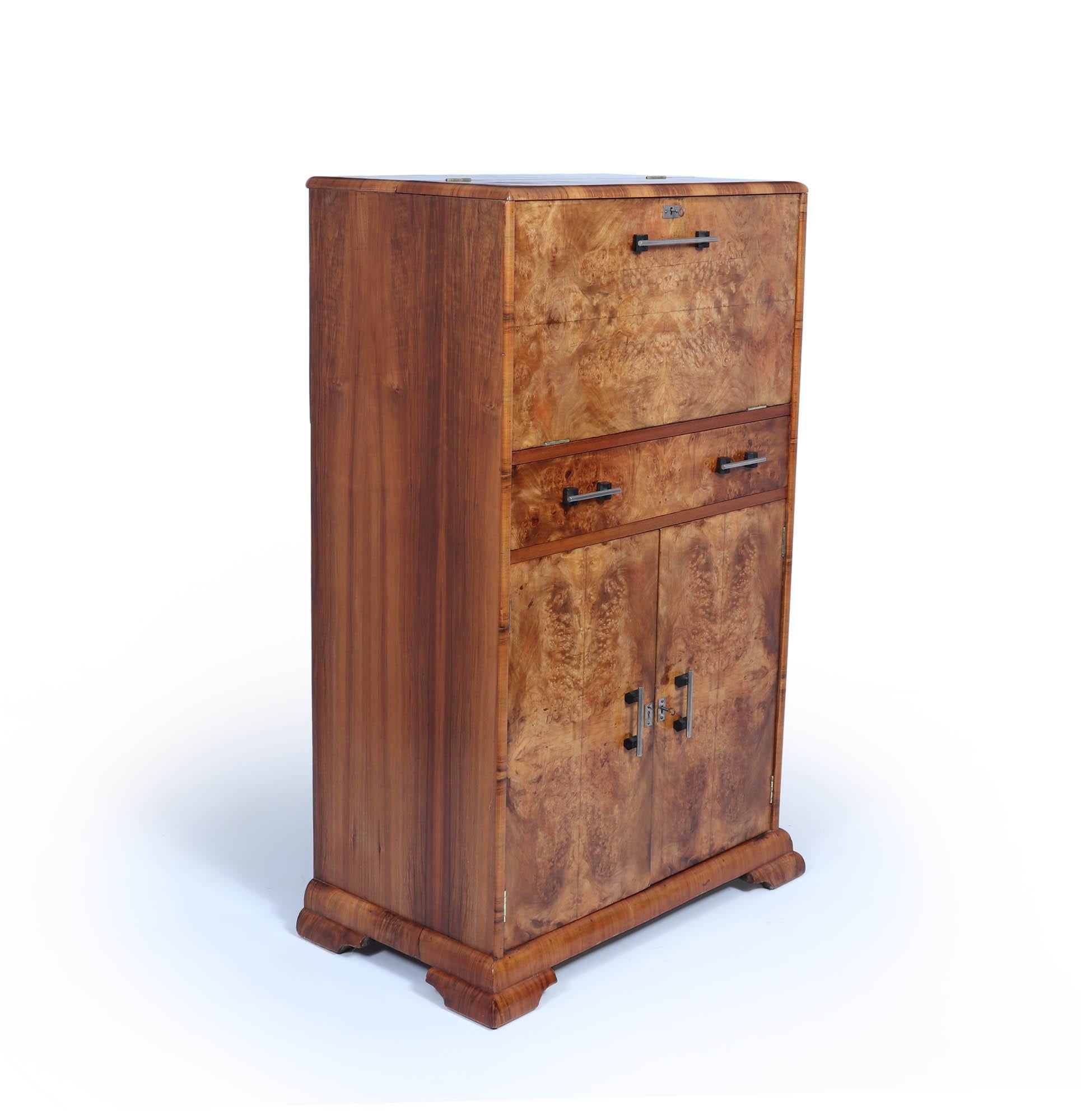 Art déco-Cocktailschrank 
Diese Cocktailbar aus Wurzelnussholz hat ein mechanisch aufklappbares Oberteil, eine zentrale Schublade darunter und einen abschließbaren Ablageschrank am Boden. Sie wurde vollständig restauriert und befindet sich in einem