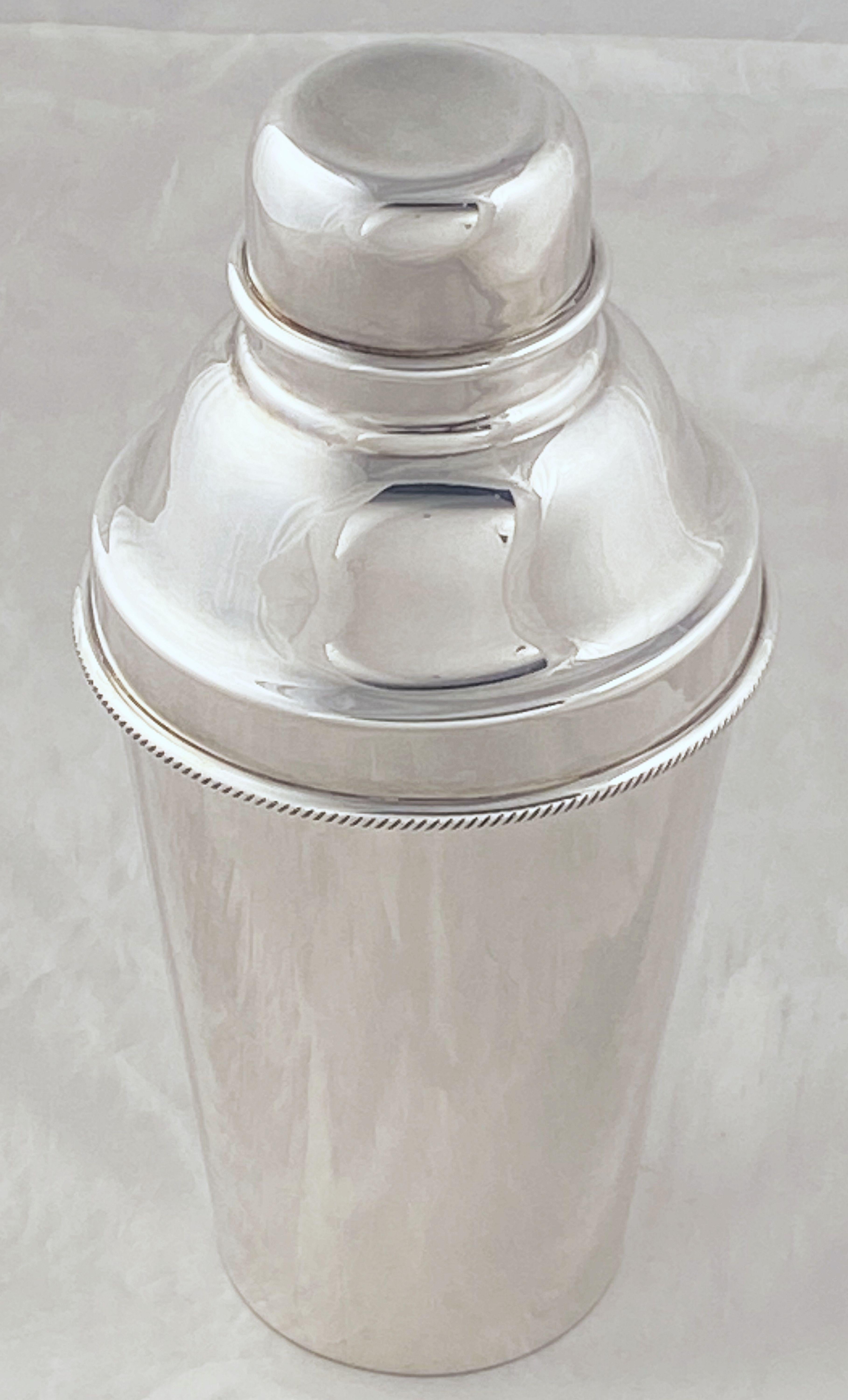 A vintage English cylindrical martini or cocktail shaker of fine plate silver from the Art Deco period, with engine-turned removable CAP and strainer.

Marked on base: EPNS (Pineapple) for Barker-Ellis, Birmingham, UK

Barker-Ellis was