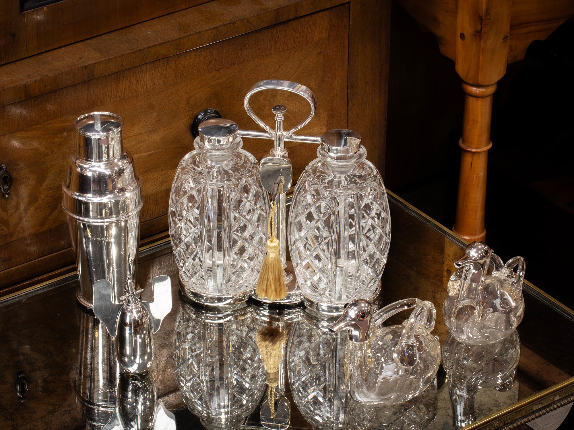Art Deco CIRCA 1920

Aus unserer Tantalus-Kollektion bieten wir Ihnen diesen Tantalus von Hukin and Heath im Art Deco-Stil an. Der Tantalus ist mit zwei gesteppten, ananasförmigen Dekantern modelliert, die durch einen Rahmen aus Silberblech
