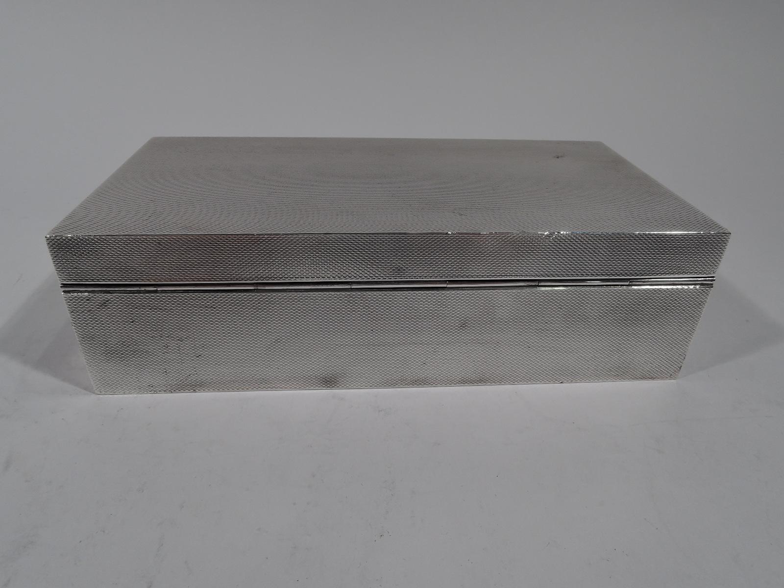 Art Deco sterling silver box. Made by CJ Vander in London in 1963. Rectangular with straight sides. Cover hinged, tabbed, and flat. Allover engine-turned wavy lines. Box and cover interior cedar lined and partitioned. Box underside leather lined.