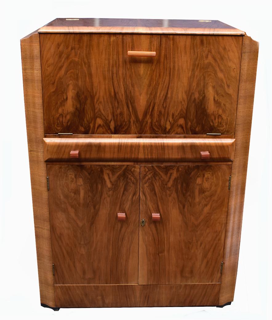 Beautiful 1930s Art Deco walnut upright cocktail cabinet, every deco interior should have one of these ! Features a drop down top which reveals a mirrored interior and storage glasses. A generously sized cupboard below offers plenty of storage of