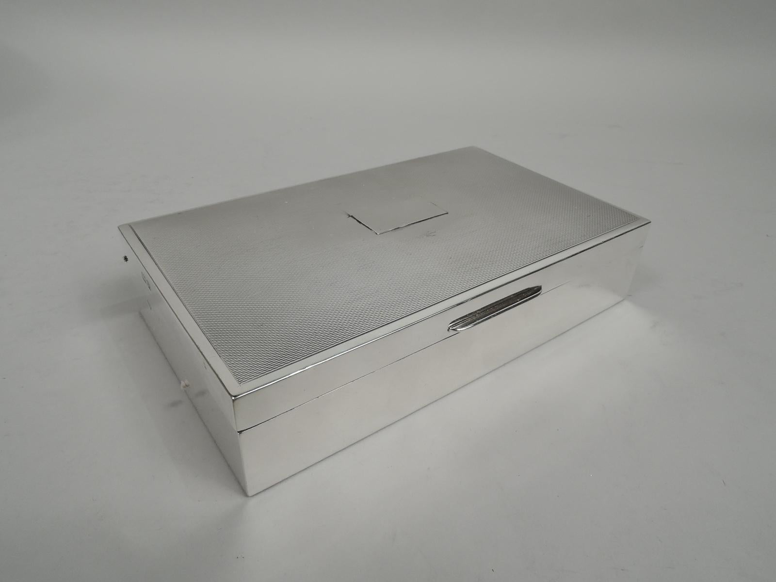 Art Deco sterling silver box. Made by E. & N. Speak in Birmingham in 1955. Rectangular with plain and straight sides. Cover hinged and tabbed; top gently curved with allover engine-turned ornament in plain border and applied central rectangular