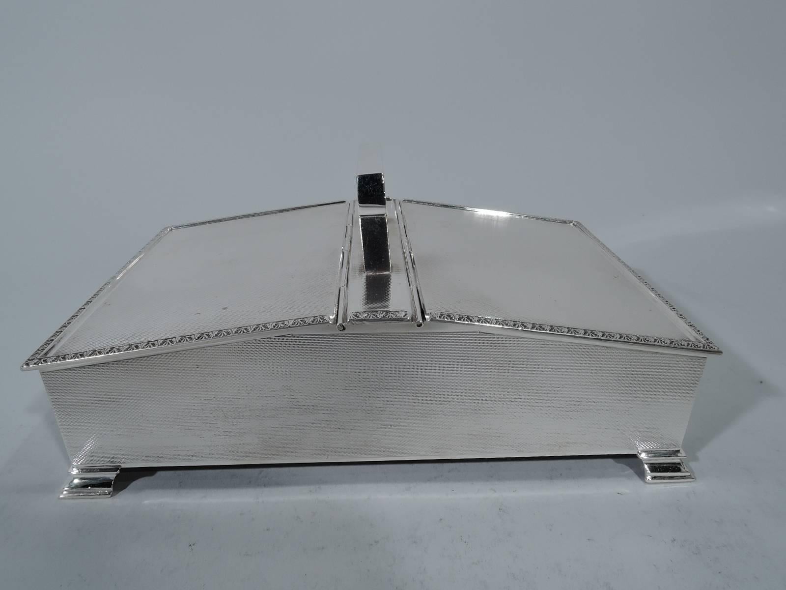 Art Deco sterling silver cigarette box. Made by William Henry Manton in Birmingham in 1964. Rectangular with straight sides. Bracket handle mounted to central panel between two sloping hinged cover. All-over engine-turned wave ornament. Top has