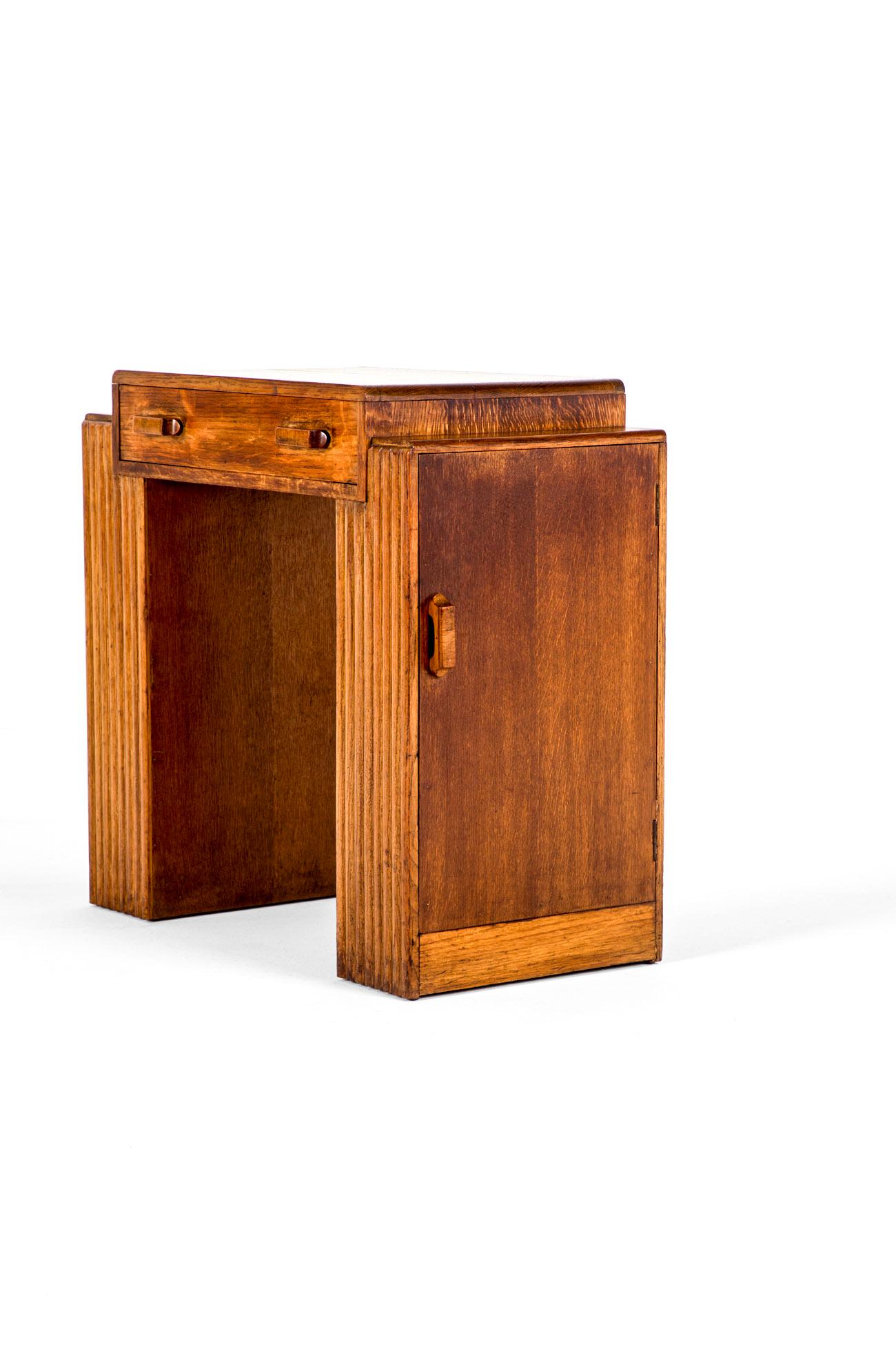 Ein ungewöhnlich kleiner Eichenschreibtisch aus der Zeit des Art déco.

Die Schreibtischplatte hat eine lange, glatt laufende Friesschublade mit Eichengriffen, die von zwei Sockeln mit geriffelten Details flankiert wird.

Die Sockel sind mit