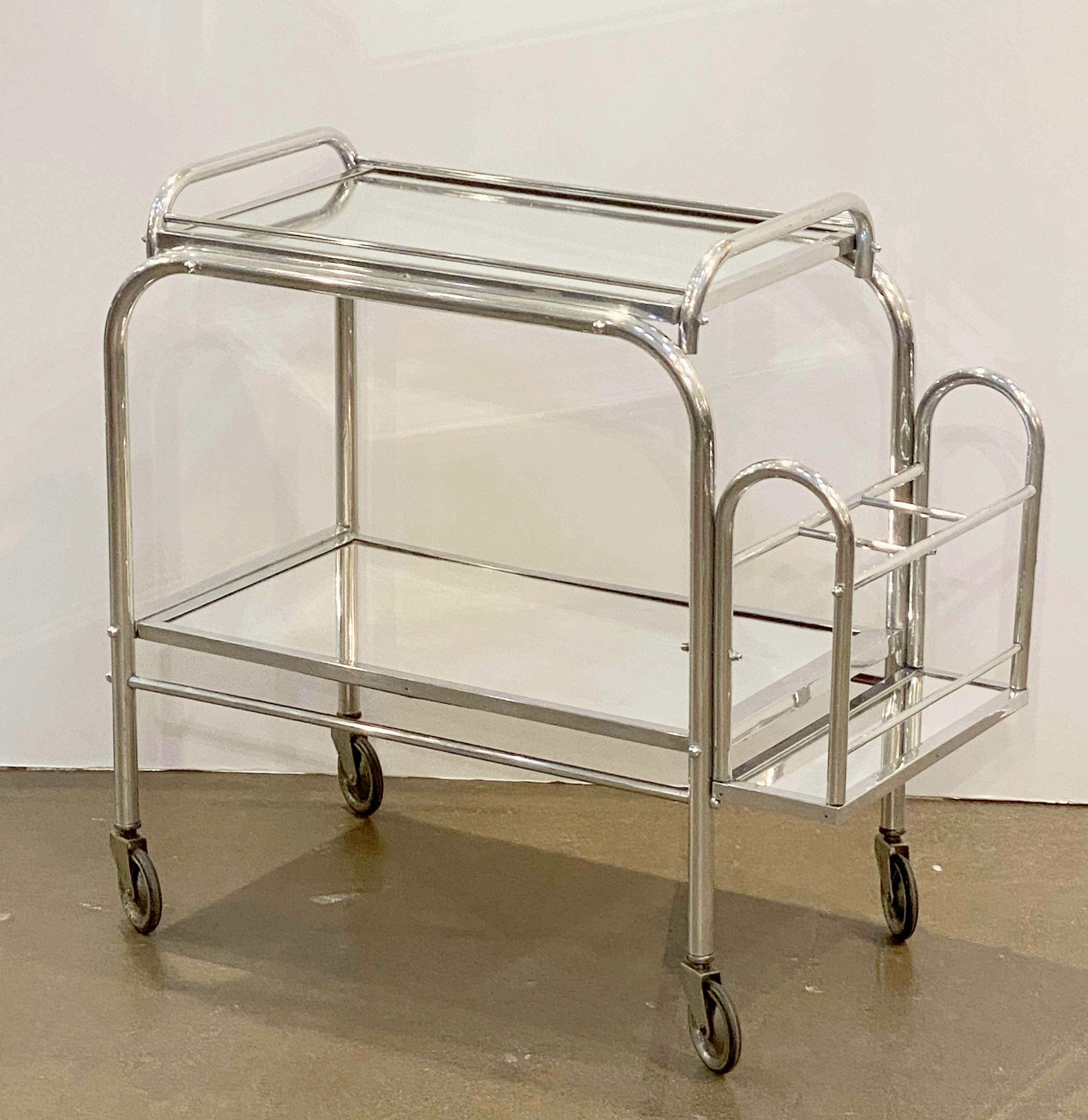 A fine English Art Deco era bar cart or drinks cart of brushed aluminum, featuring two rectangular mirrored glass tiers on stylish brushed aluminum mounts, and resting on vintage rolling casters. With removable top serving or drinks tray.