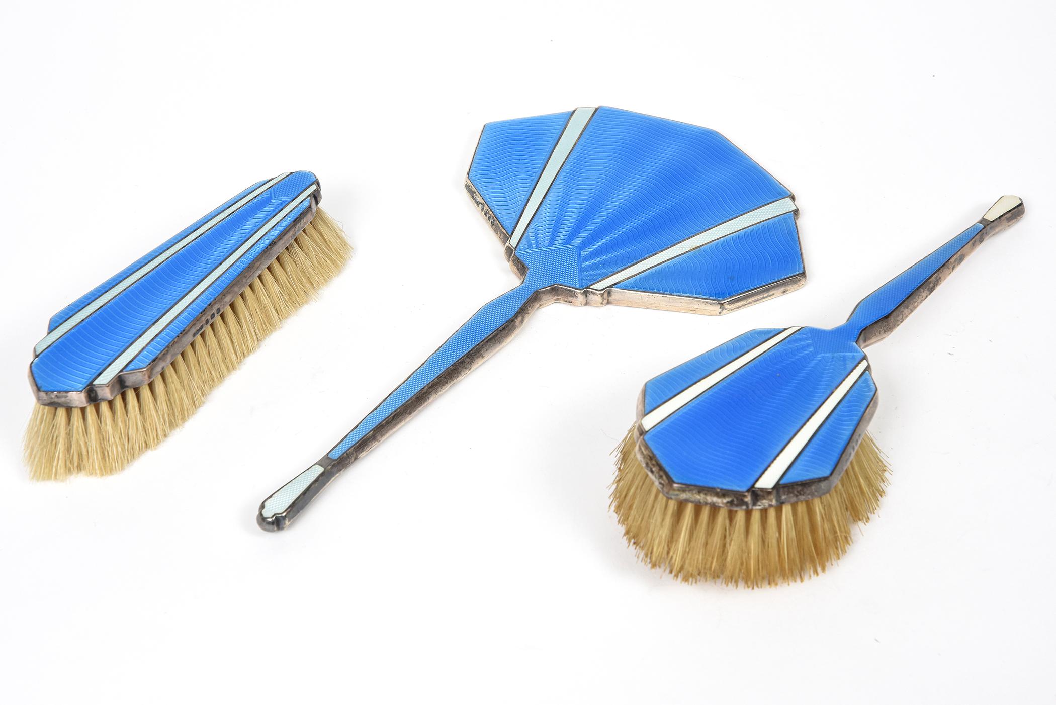 Beautiful blue guilloche enamel and sterling silver three piece brush set featuring a mirror and 2 brushes. This set was made in Birmingham England by D.M. & Co. Davis, Moss & Co. The mirror and the hand held brush are dark blue with a lighter blue