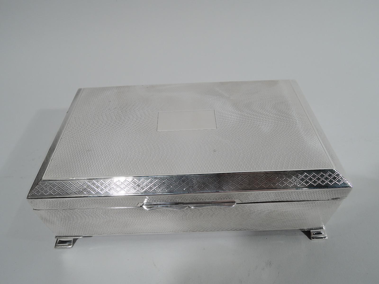 English Art Deco sterling silver box, 1946. Rectangular with straight sides. Cover flat, hinged, and tabbed with central rectangle (vacant). All-over engine-turned wave ornament on sides and cover. Cover rim faceted with geometric border. Plain